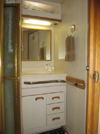 1994 Sea Ray 500 Sundancer bathroom with mirror, sink, and storage cabinets.