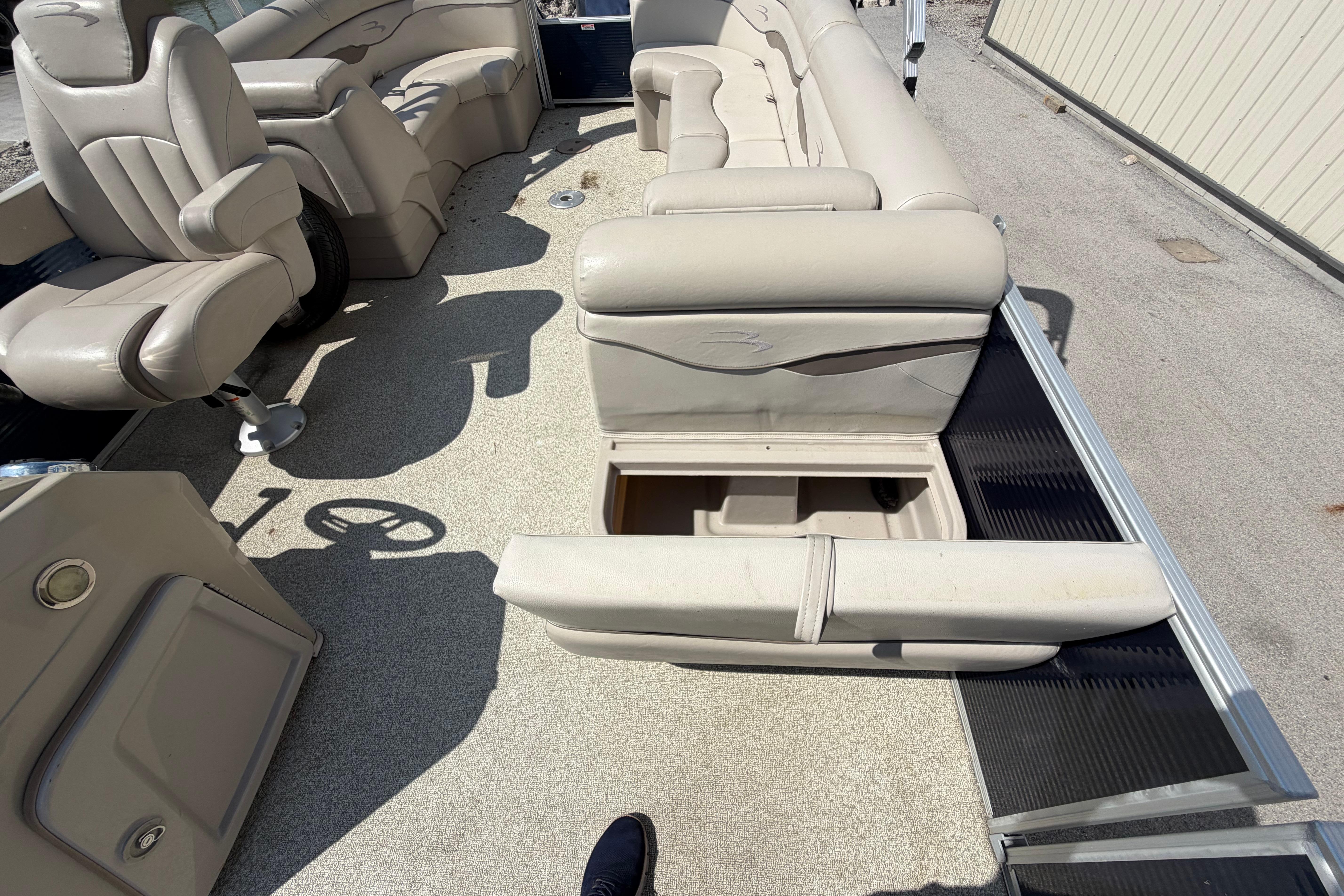 Interior of 2017 Bennington 25 SSXAPG pontoon boat with beige seating and storage compartment.