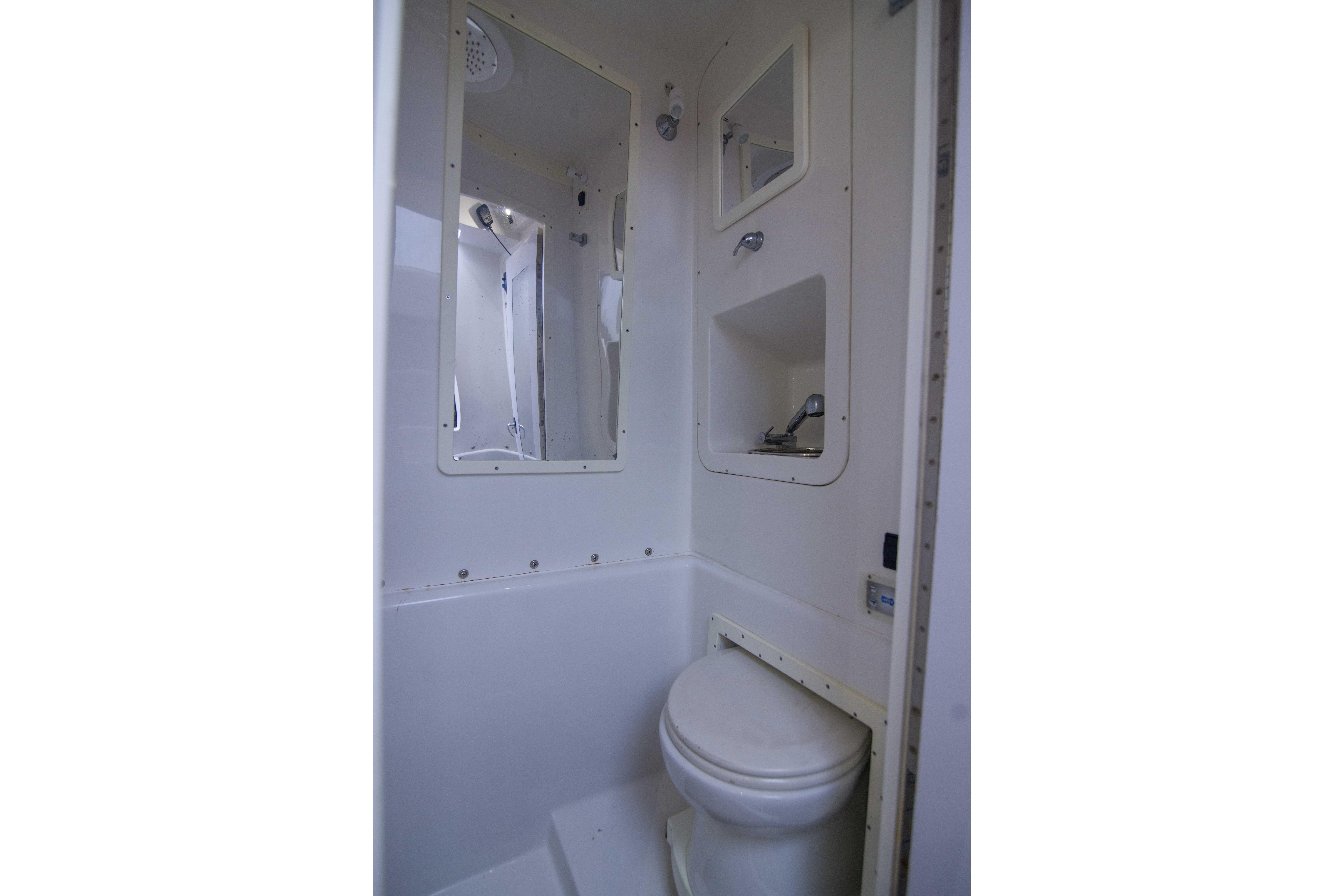 Compact bathroom in 2019 Midnight Express 43 Open boat, featuring toilet and mirror.