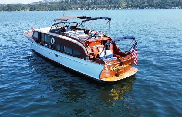 1951 Chris-Craft Catalina boat on a lake, featuring classic wooden design and American flag.