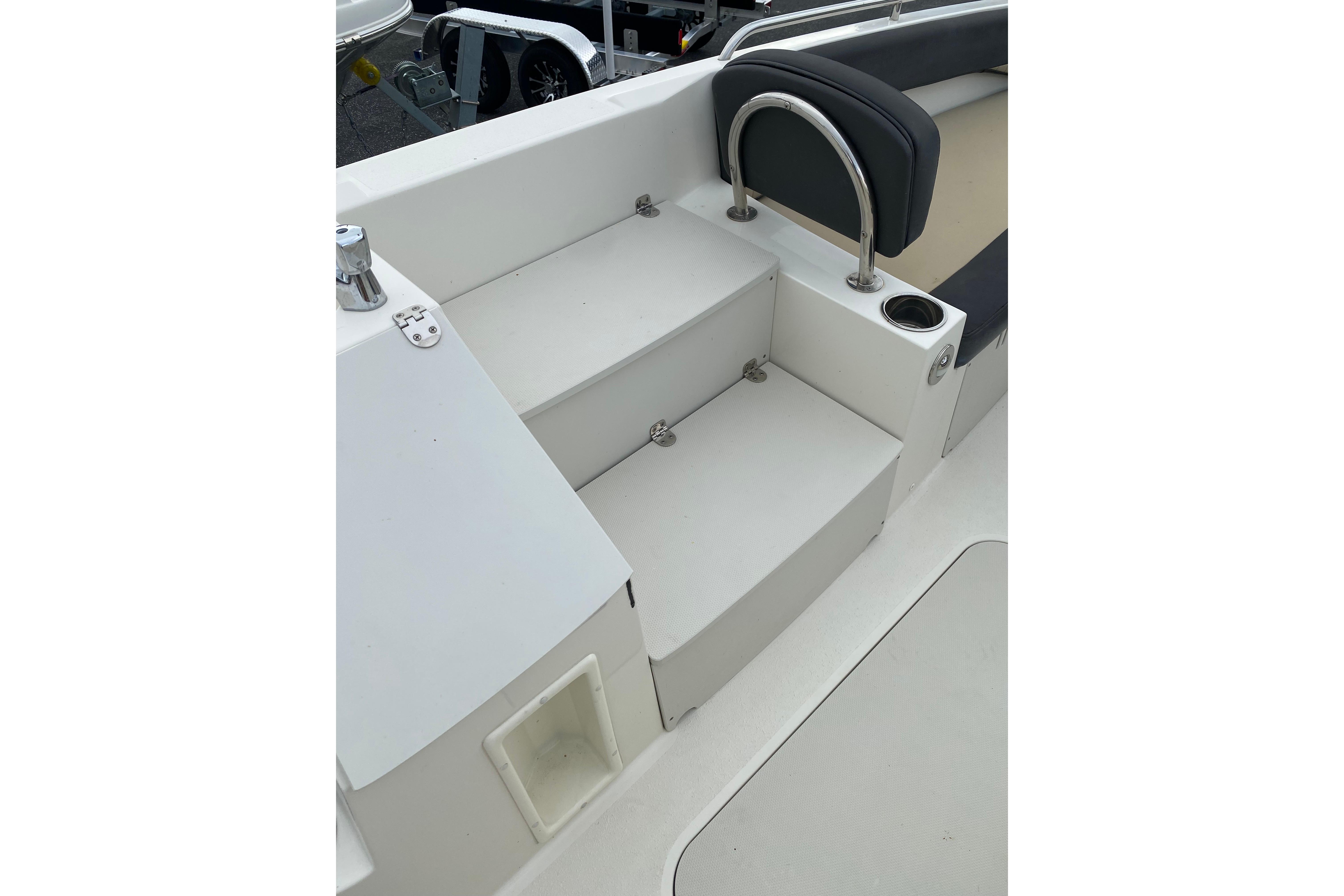 2018 Stingray 212 SC boat interior with seating and steps, featuring cup holder and railing.