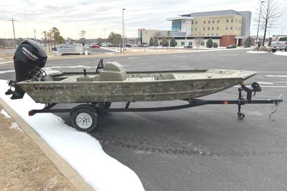 2025 Tracker Grizzly 1648 SC boat on trailer in parking lot, overcast sky.