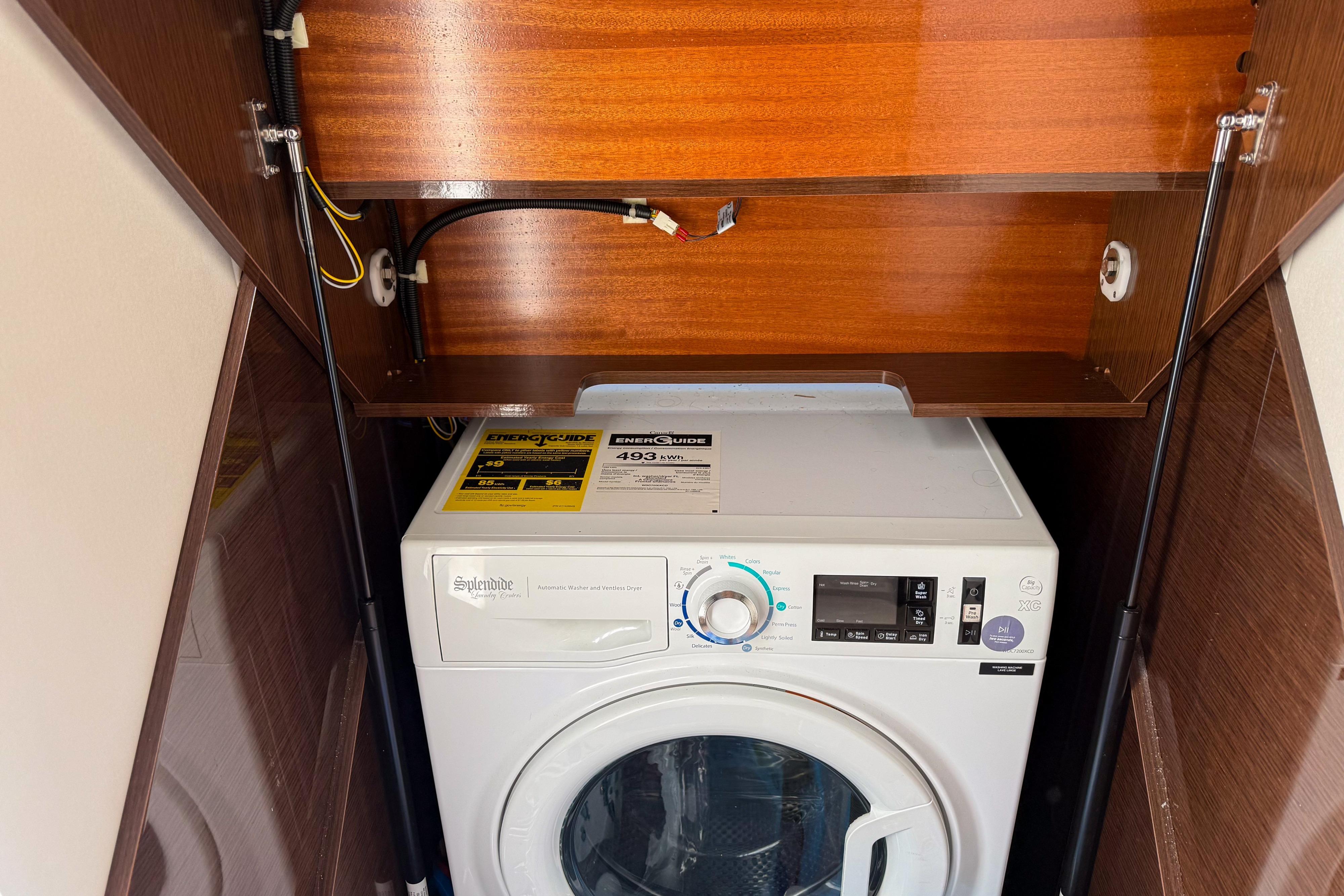 2023 Prestige 590 laundry area with Splendide washer-dryer, wooden cabinet, and energy guide label.