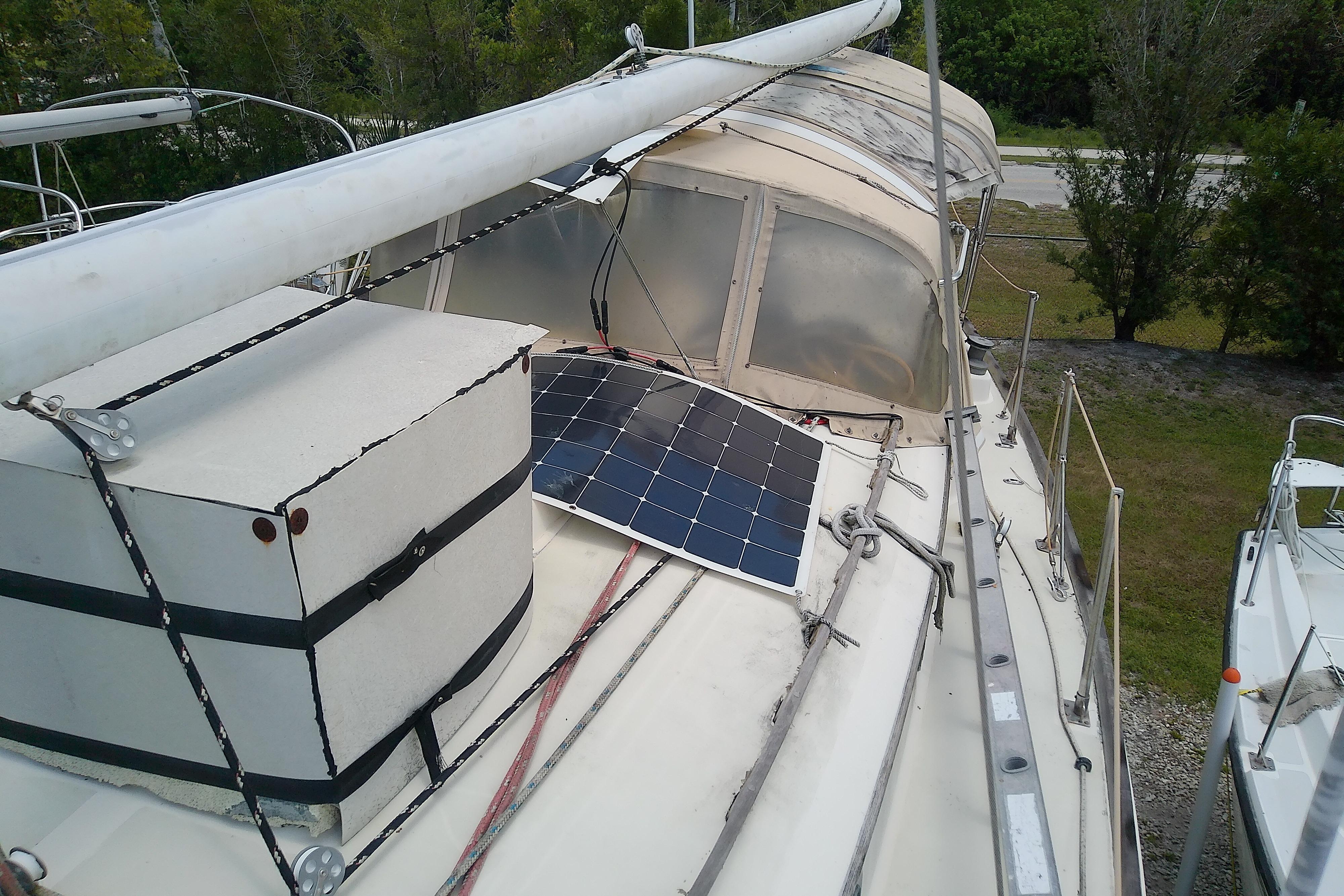 1981 Sea Sprite 34 sailboat with solar panel on deck, docked near trees.