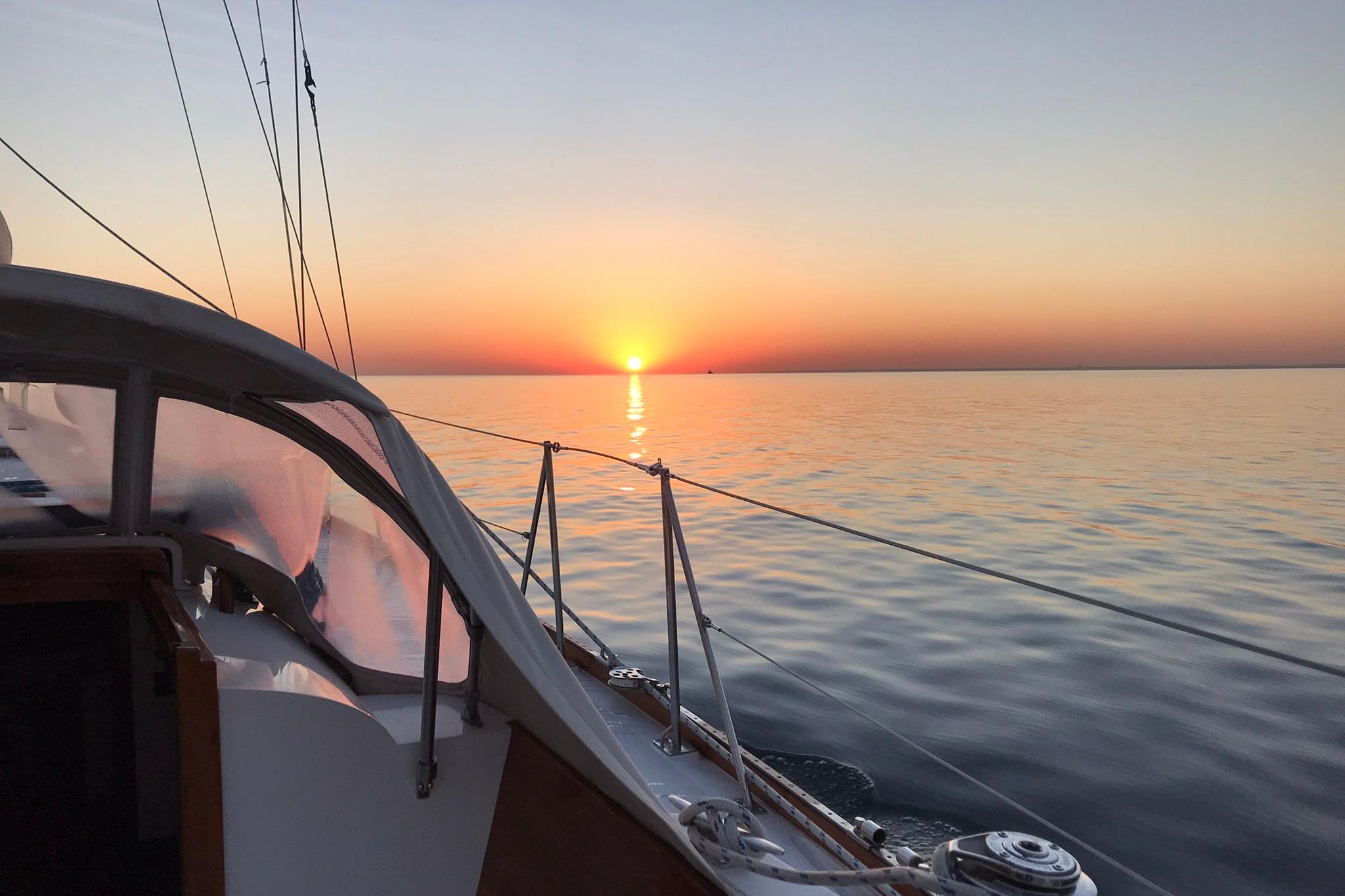 Hinckley Bermuda 40 sailboat at sunset on calm ocean waters, 1970 model.