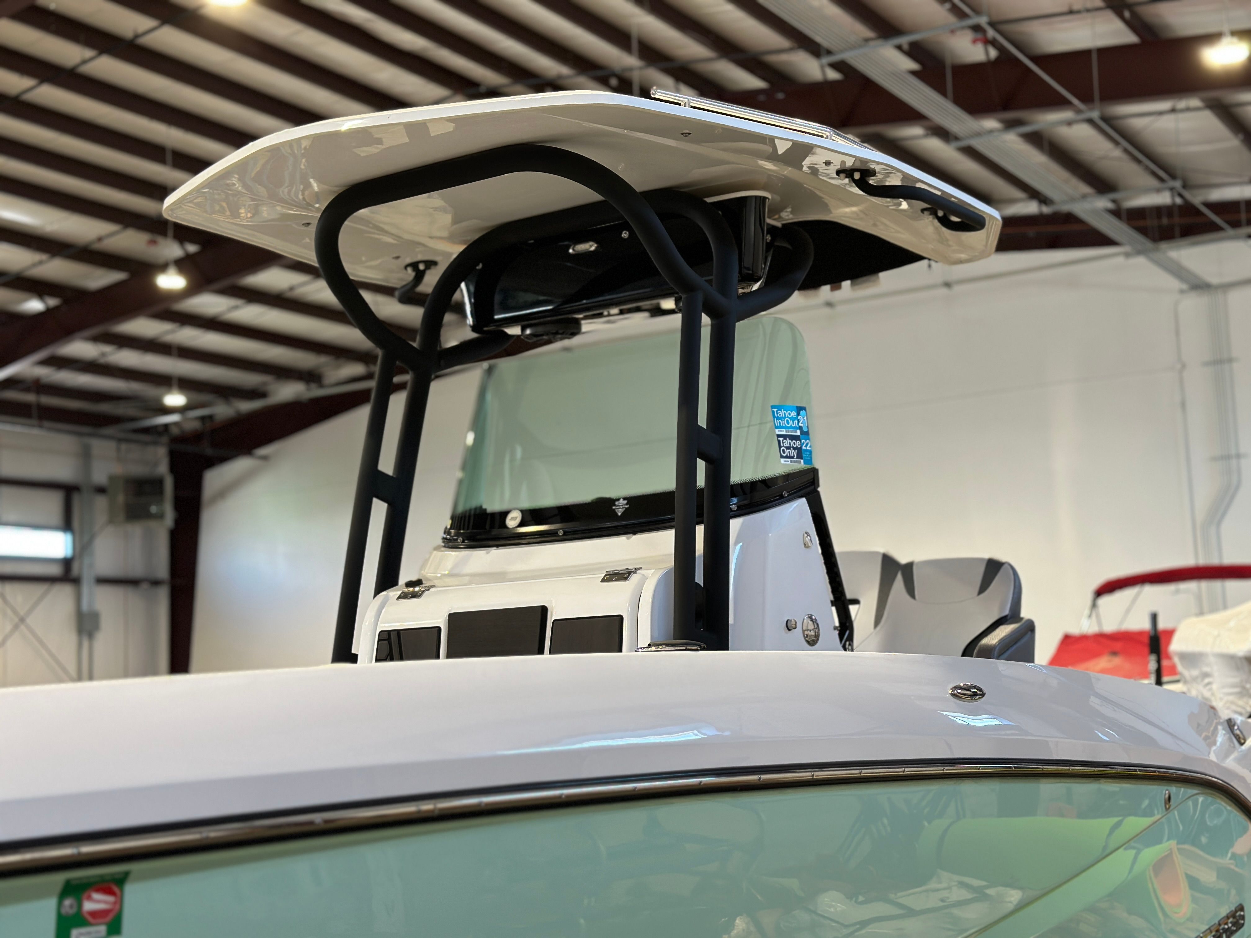 A 2021 Scarab 255 Open ID boat in a warehouse. It features a sturdy T-top.