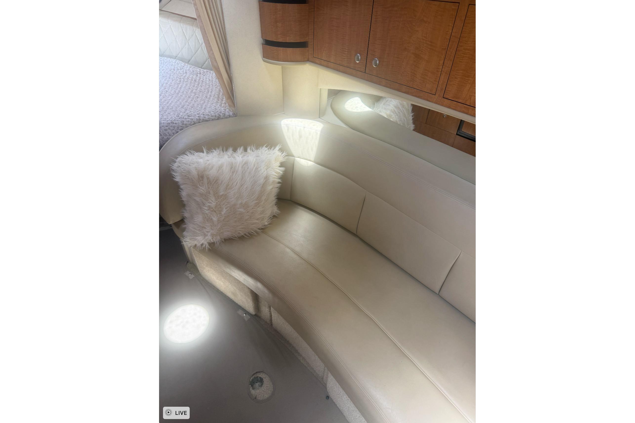 Interior of 2006 Sea Ray 300 Sundancer with beige seating and fluffy pillow.