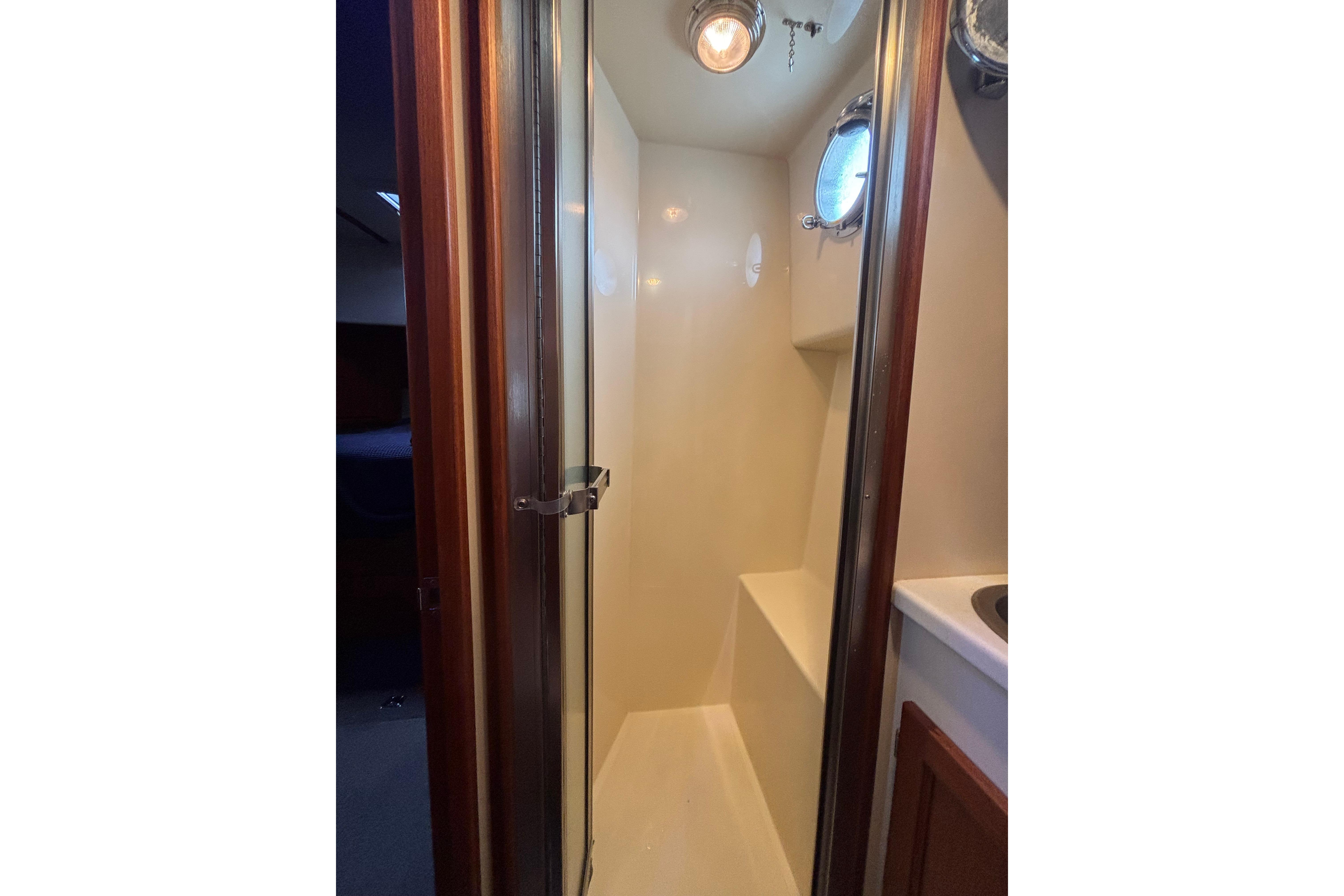 Shower area in 2004 Nordic Tug 37 boat with porthole and wooden door.