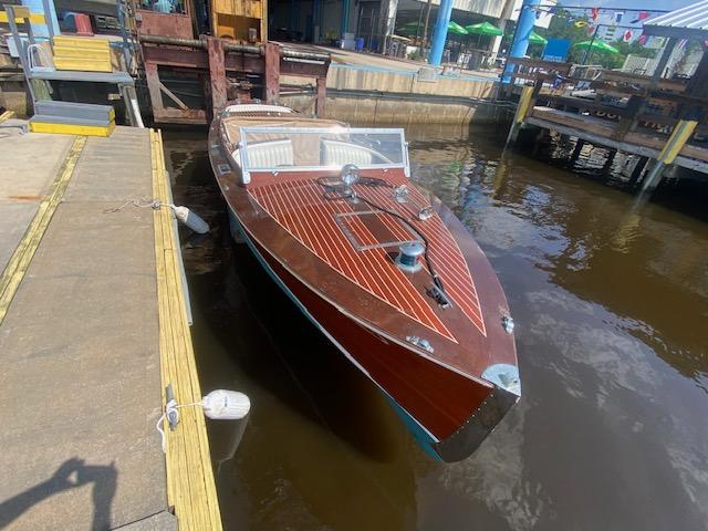 2000 Grand Craft Classic Runabout boat docked at a marina, showcasing elegant wooden design.
