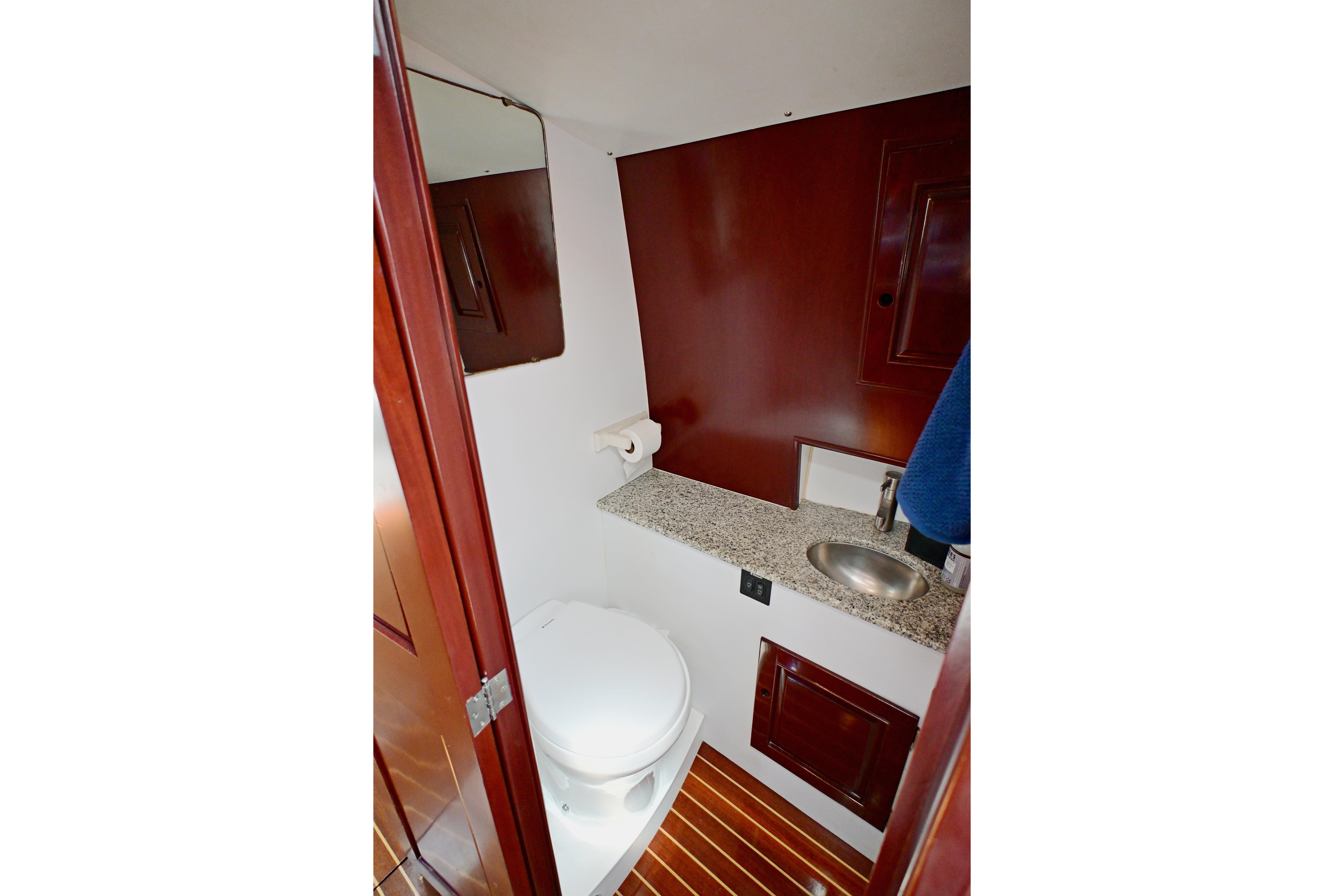 Elegant yacht bathroom with wooden accents, granite countertop, and compact sink, Abeking & Rasmussen Tripp 74, 1968.