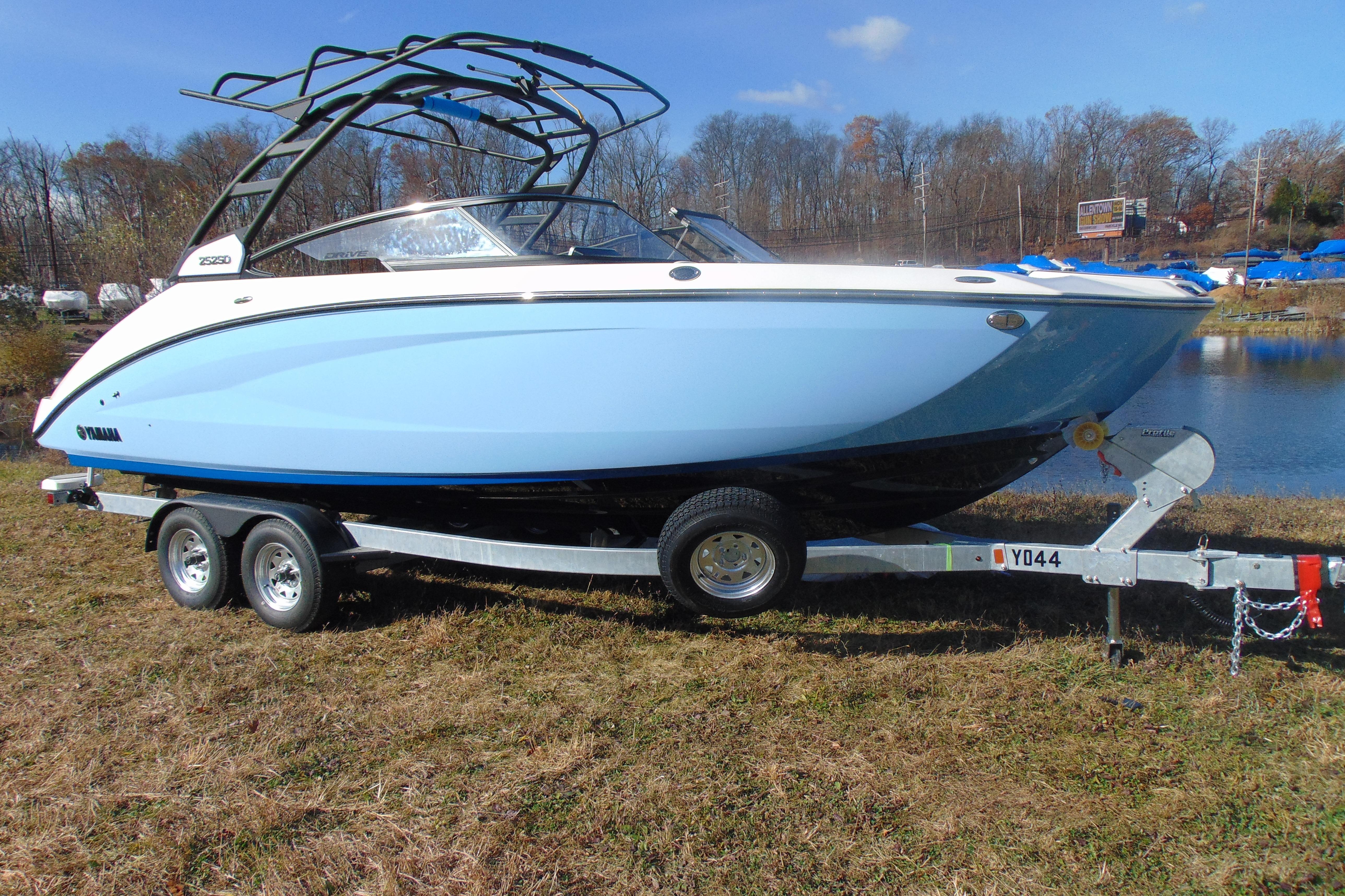 2026 Yamaha Boats 252SD on trailer, parked near a lake, under clear blue sky.