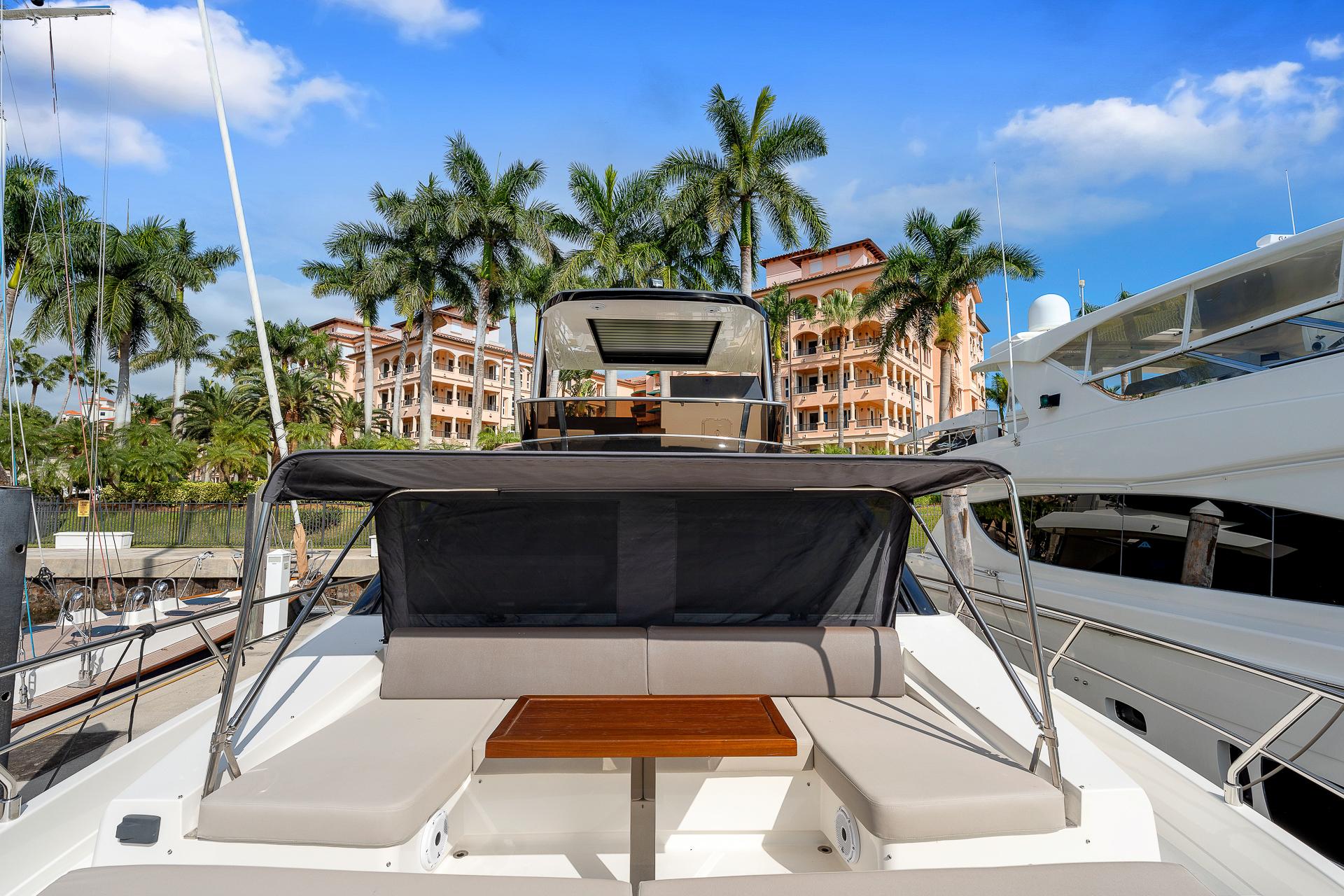 Astondoa 66 yacht, 2022 model, docked with palm trees and buildings in the background.