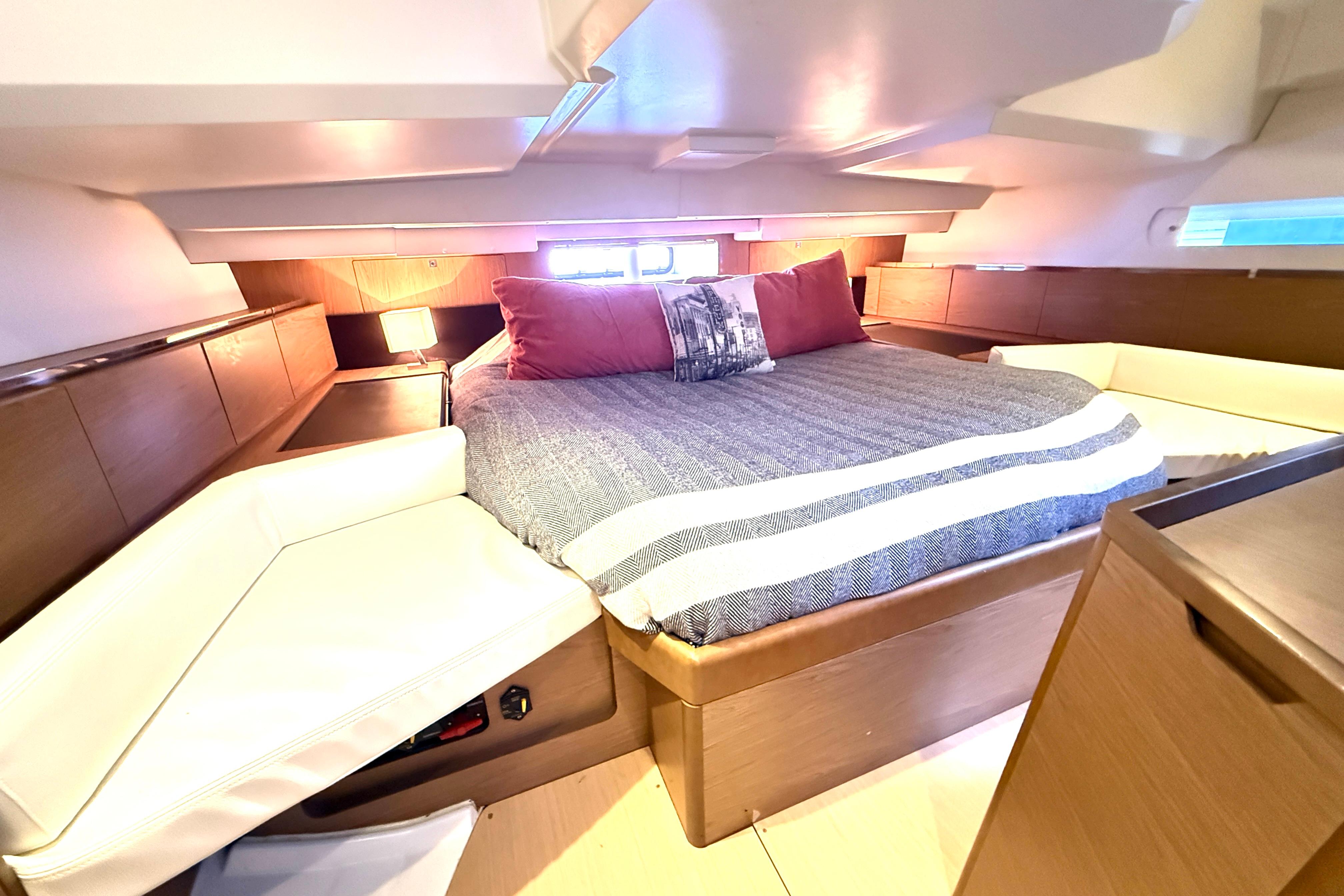 Luxurious cabin interior of 2013 Jeanneau Sun Odyssey 44 DS yacht with cozy bed and seating.