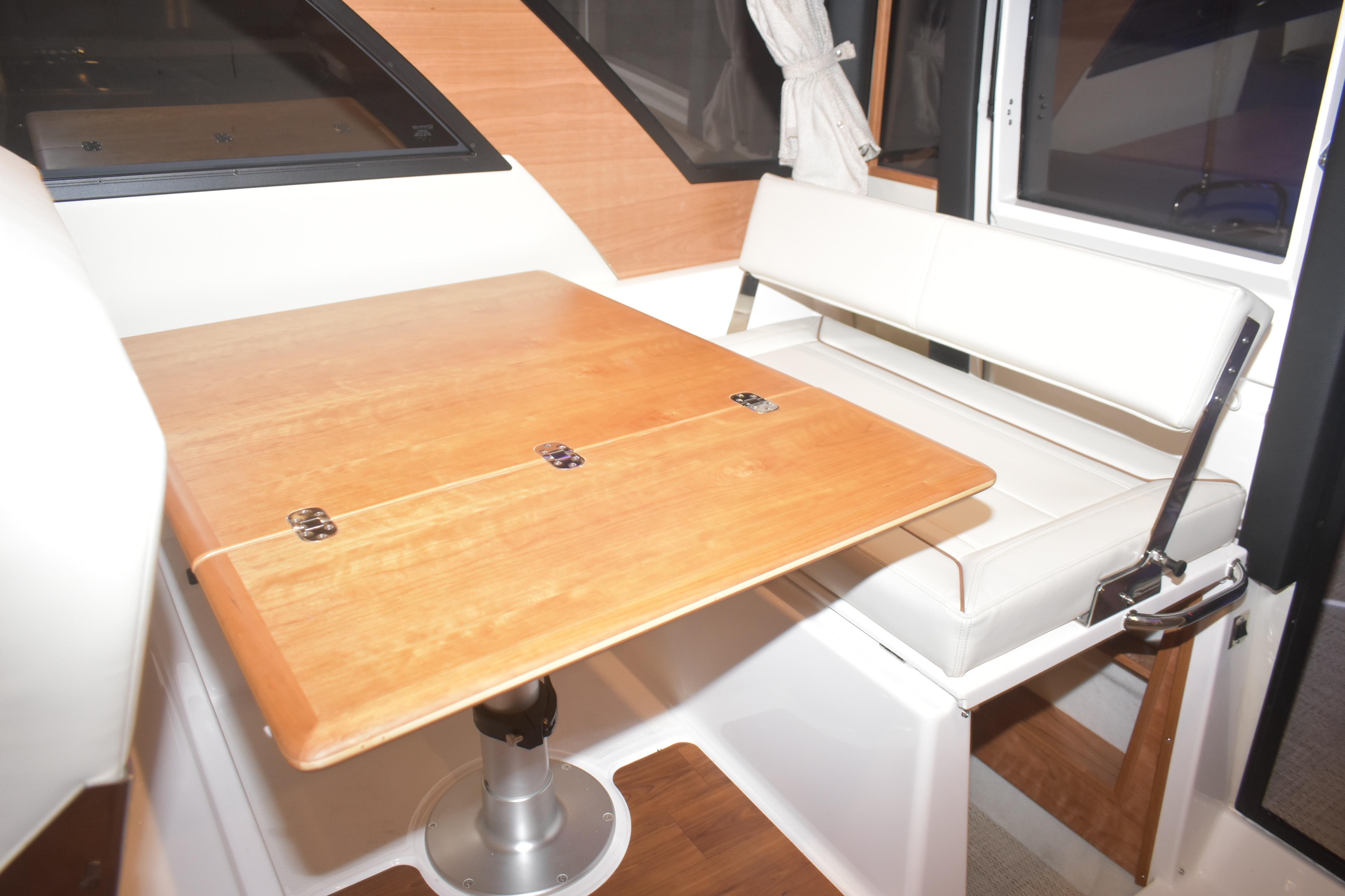 Interior of 2026 Cutwater C-32 CB boat with wooden table and white seating.
