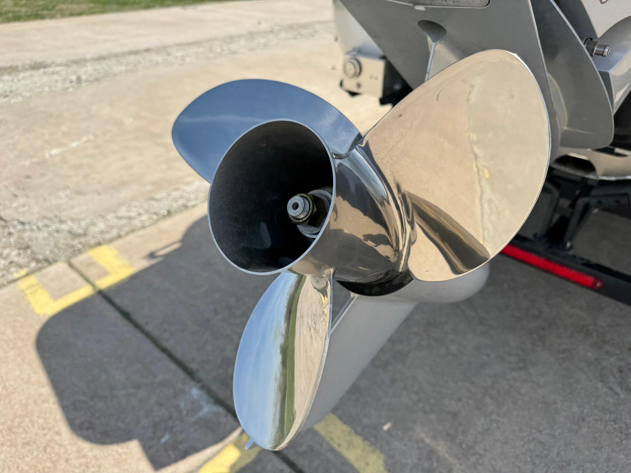 2025 Barletta Lusso 23UC boat propeller, shiny and metallic, on a concrete surface.