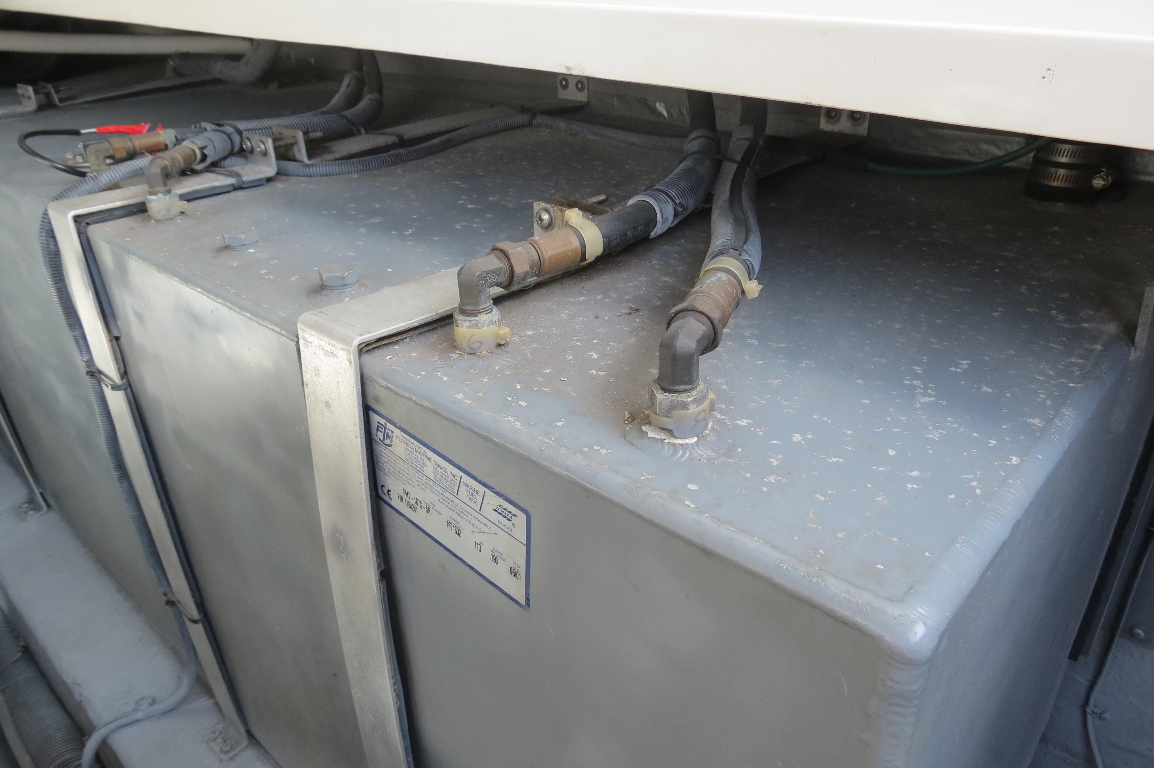 Close-up of a metal tank with hoses and fittings on a boat.