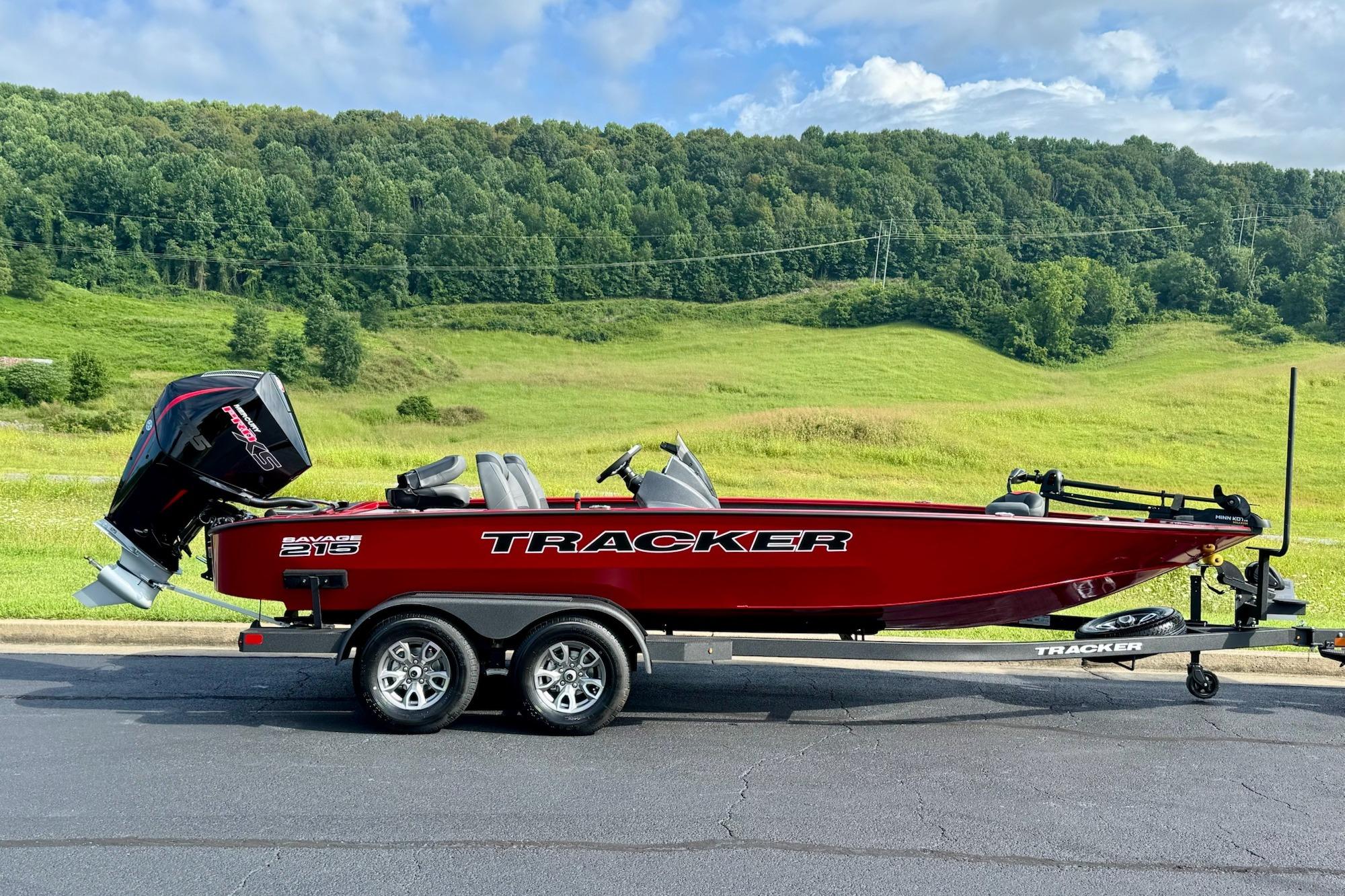 2026 Tracker Savage 215 boat on trailer, parked with scenic green hills in background.