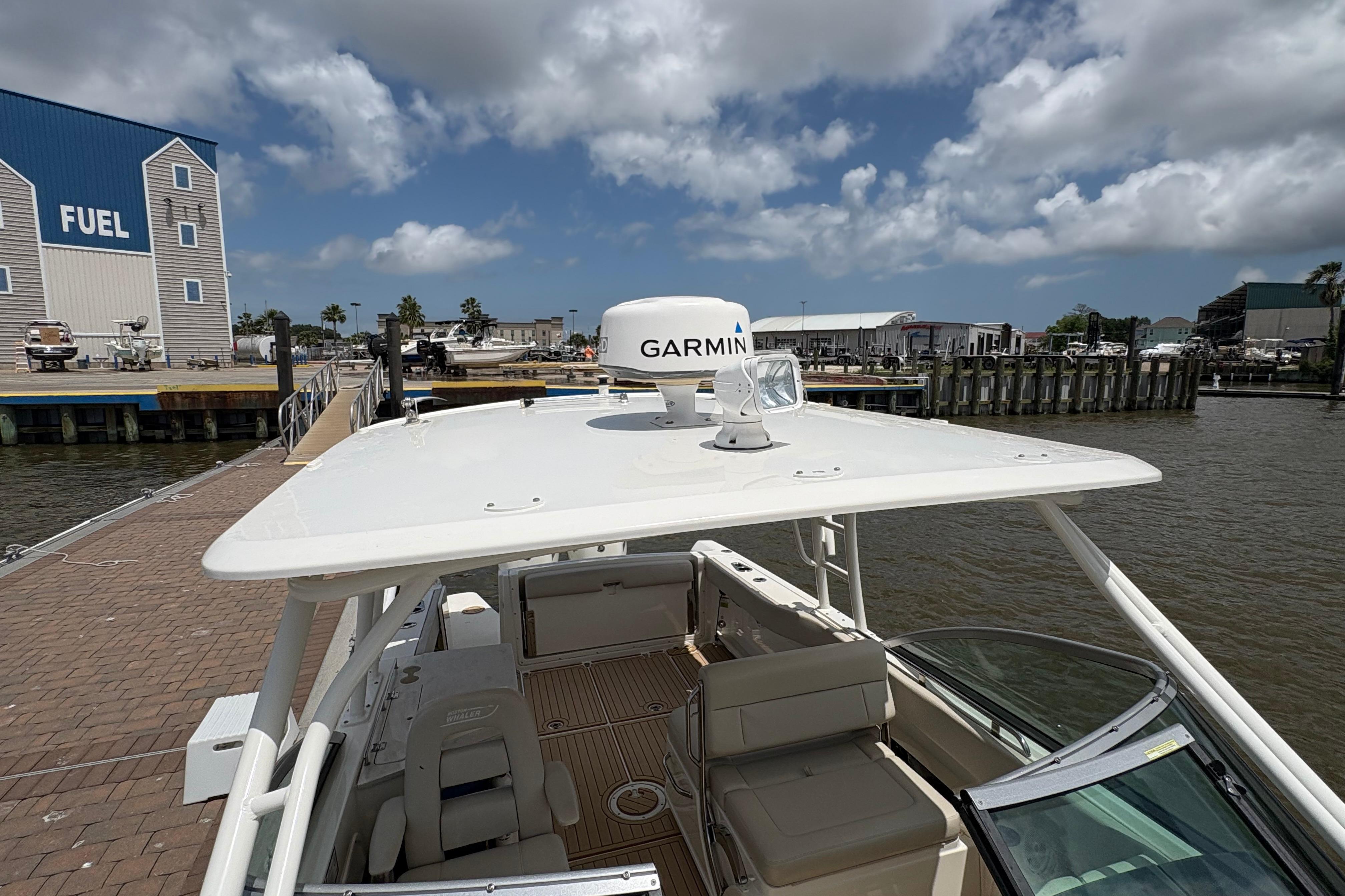 2017 Boston Whaler 270 Vantage docked near fuel station under cloudy sky.