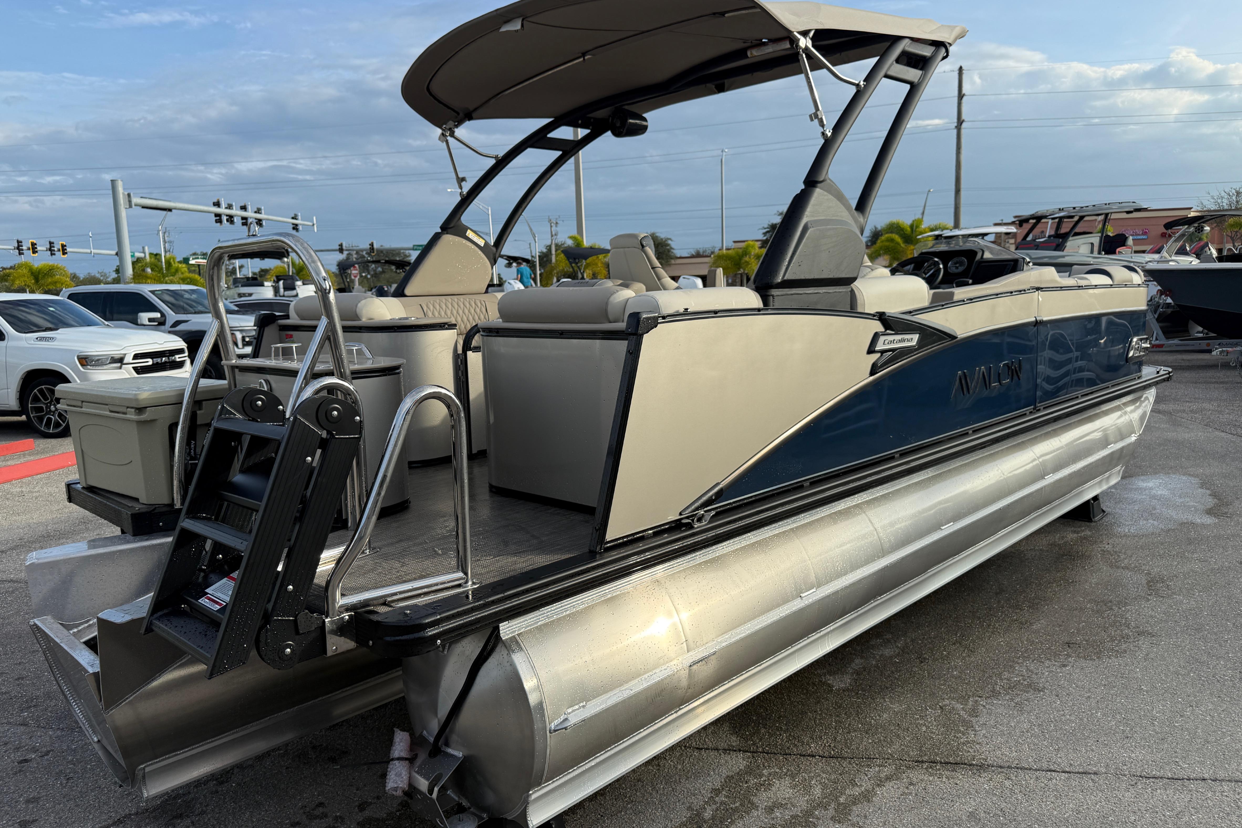 2026 Avalon 2385 Catalina Quad Lounger Tri Toon boat, parked outdoors, showcasing sleek design.