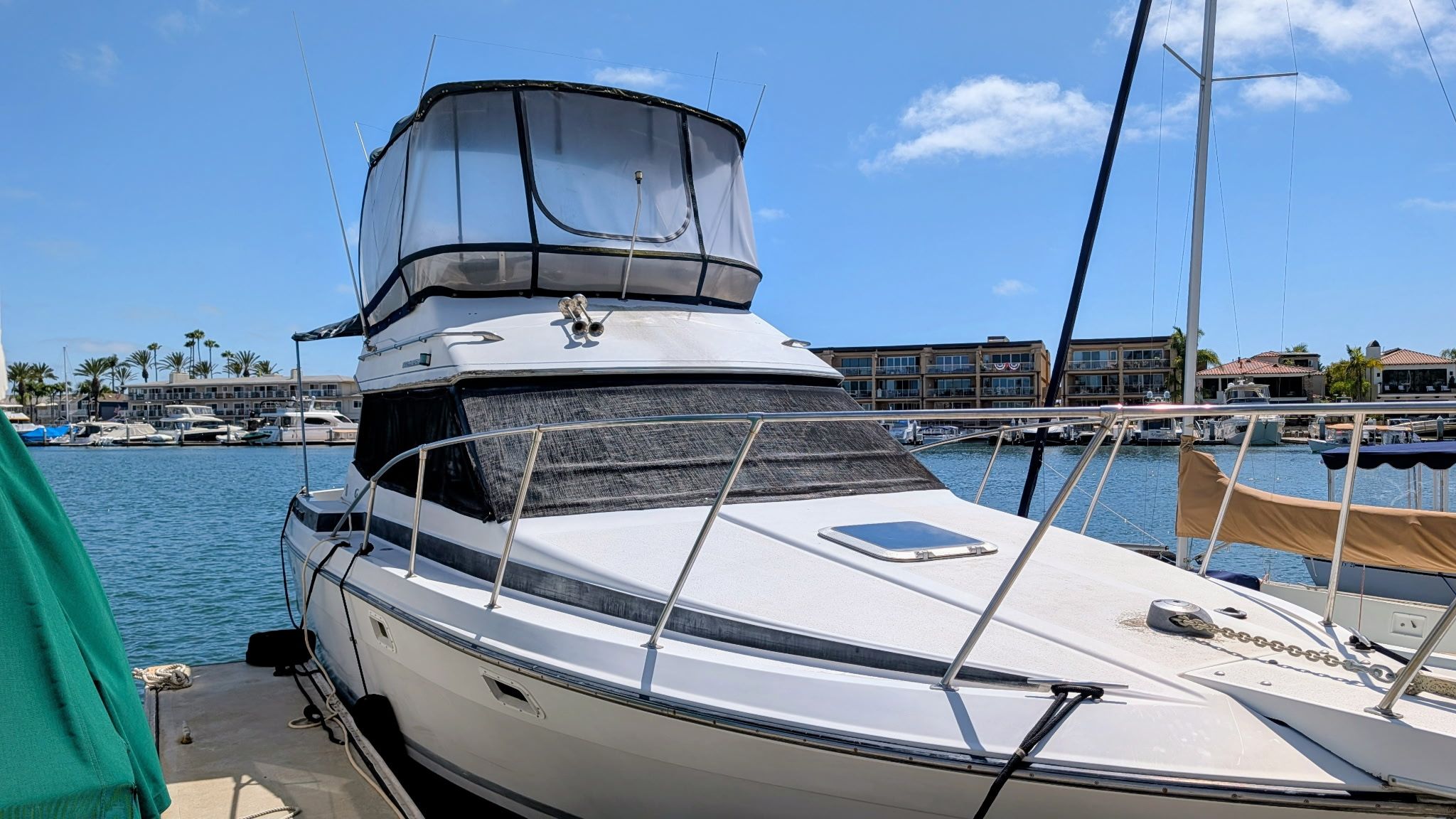 A 1987 Chris-Craft 320 Amerosport Express docked. It features an elevated helm and is surrounded by water and other boats.