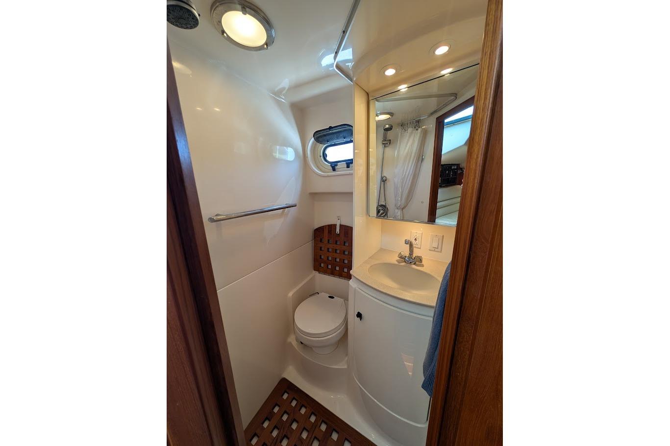Compact bathroom in a 2000 Pursuit 3400 Express boat, featuring a toilet and sink.