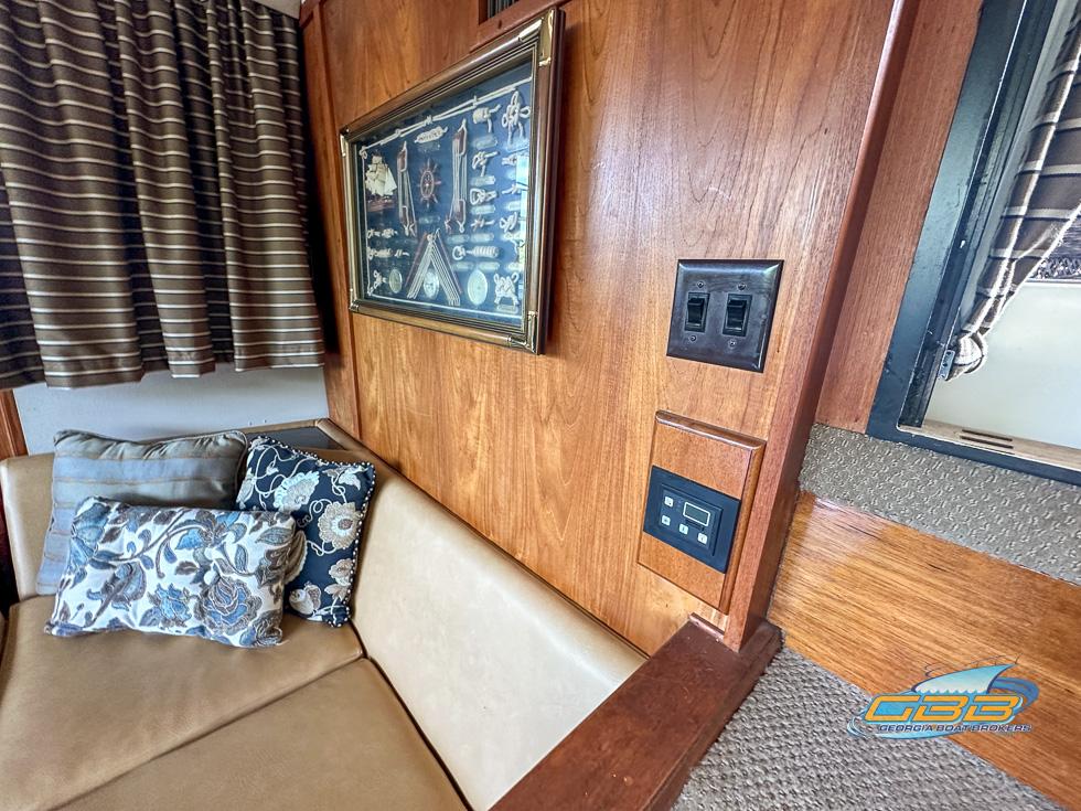1989 Carver 3807 Aft Cabin interior with wood paneling, artwork, and cushioned seating.
