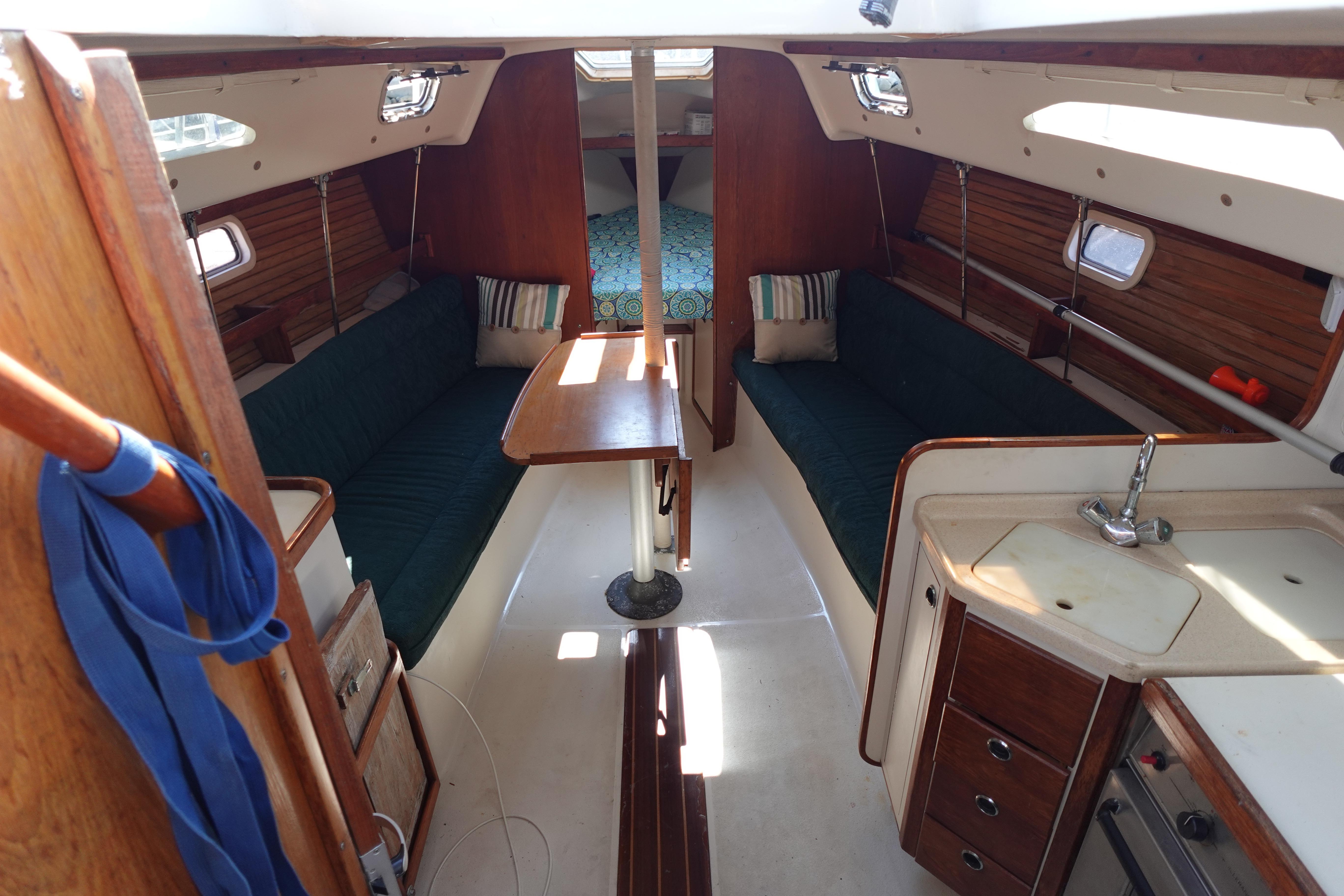 Interior of a 1997 Catalina 28 sailboat with cozy seating and compact kitchen area.