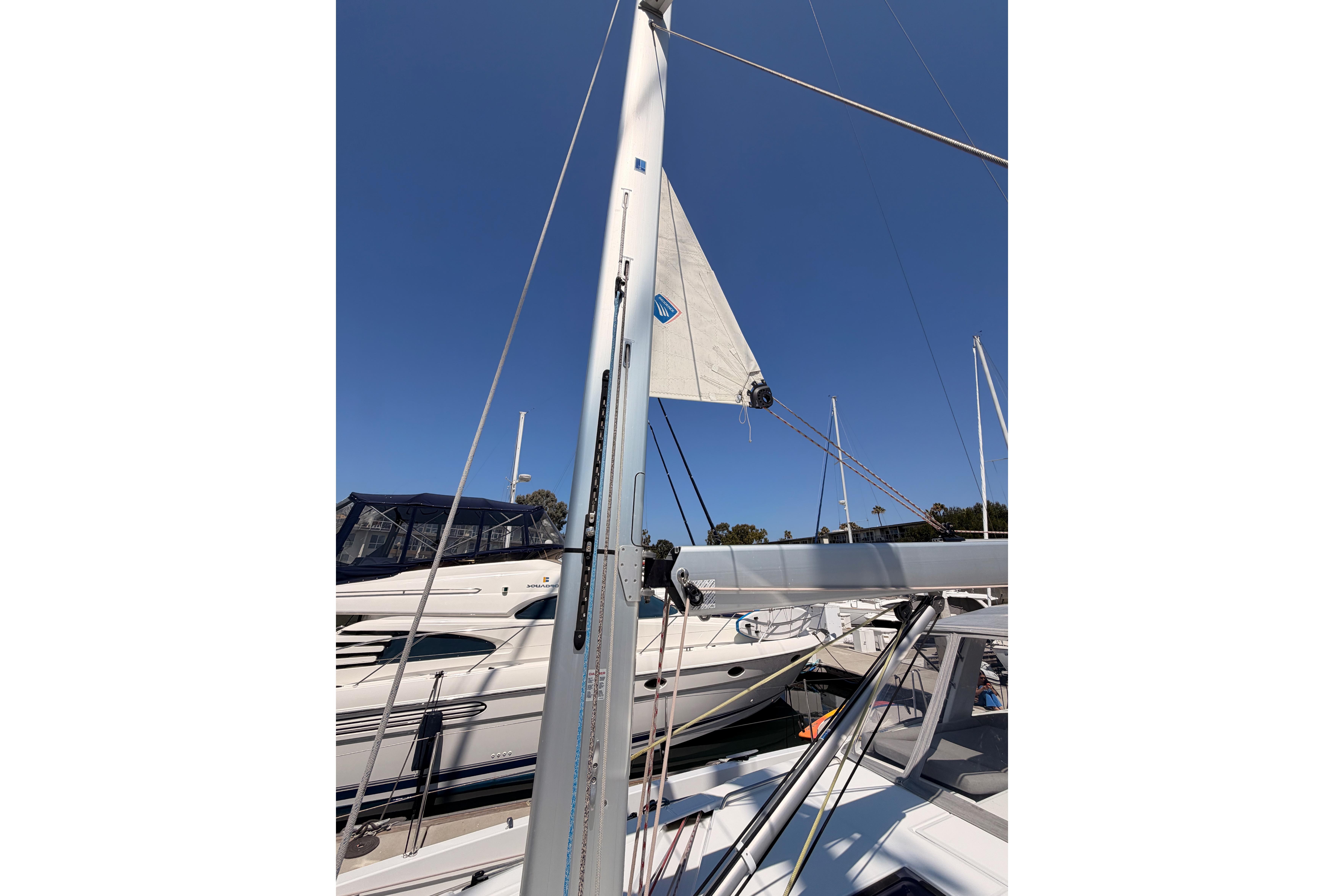 2022 Beneteau Oceanis Yacht 54 mast and sail against clear blue sky.
