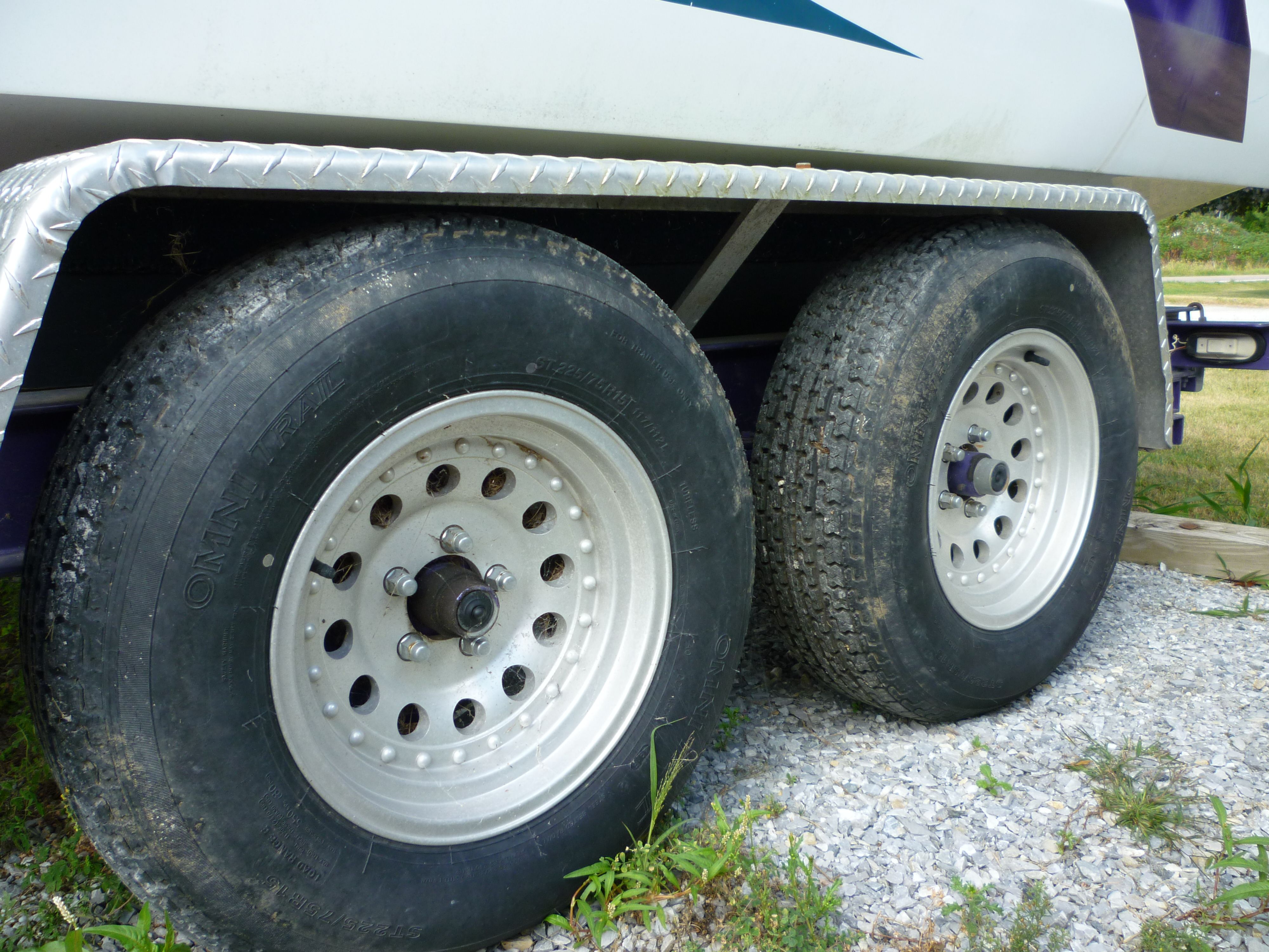 Trailer wheels of a 2000 Velocity 280 boat on gravel surface.