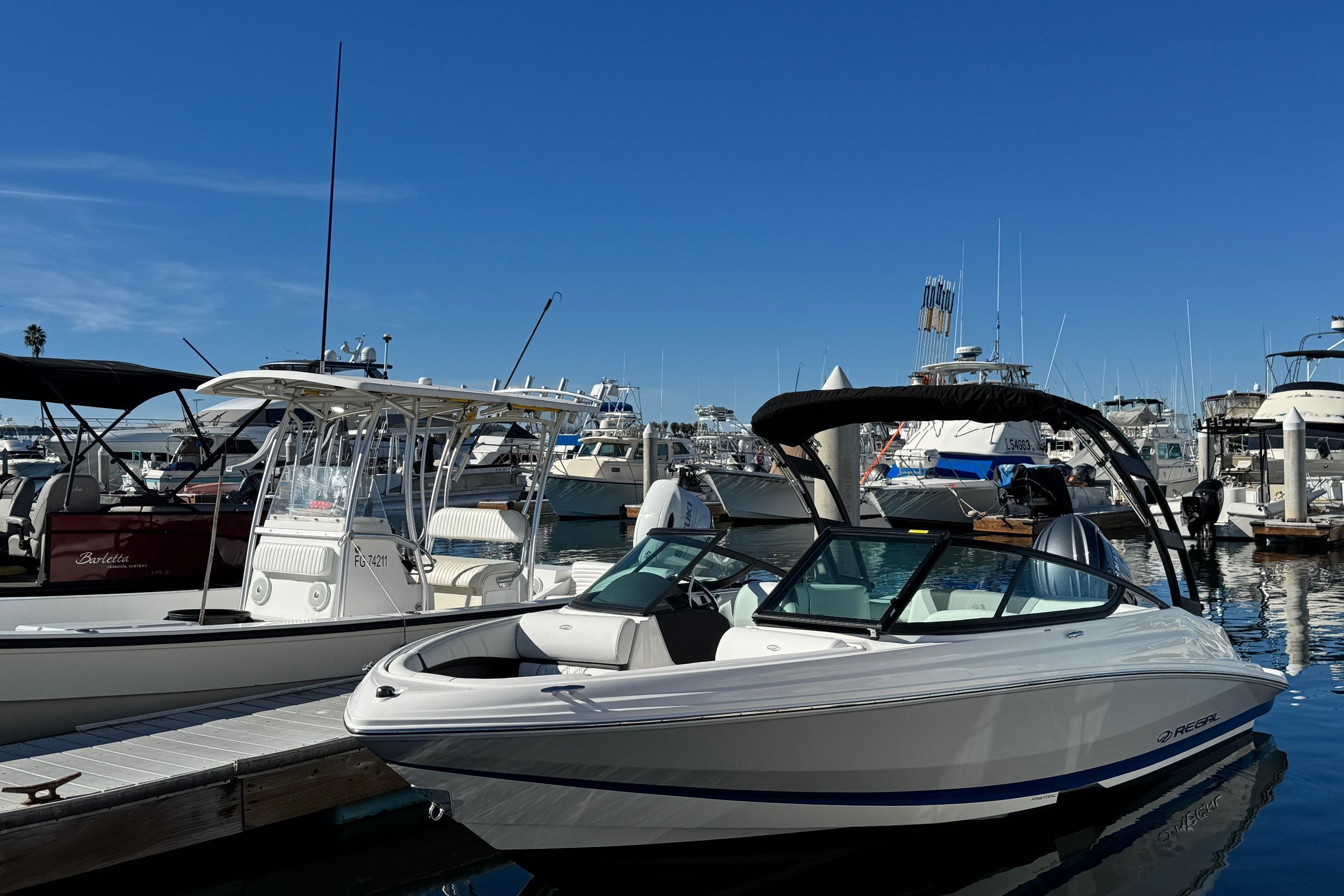 2026 Regal 21 OBX boat docked at a marina under clear blue skies.