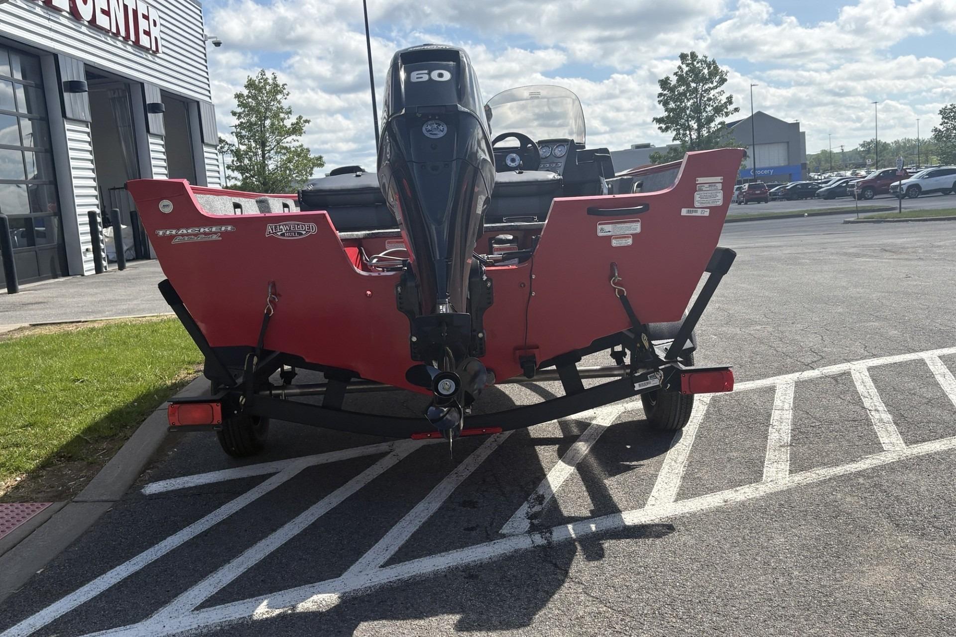 2026 Tracker Pro Guide V-16 SC boat on trailer, parked outside dealership.
