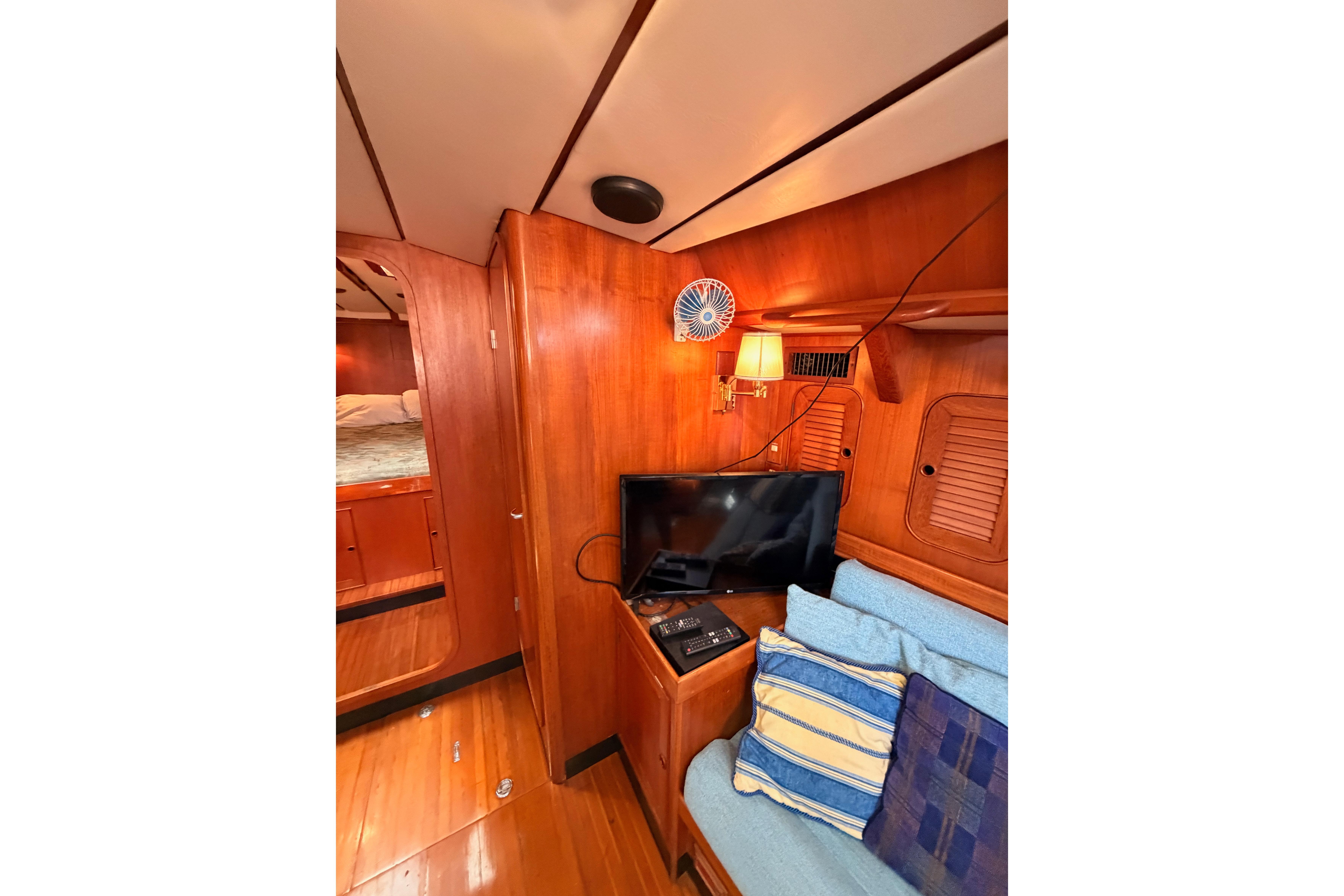 Interior of 1991 Hylas 51 yacht with wooden paneling, TV, and cozy seating area.