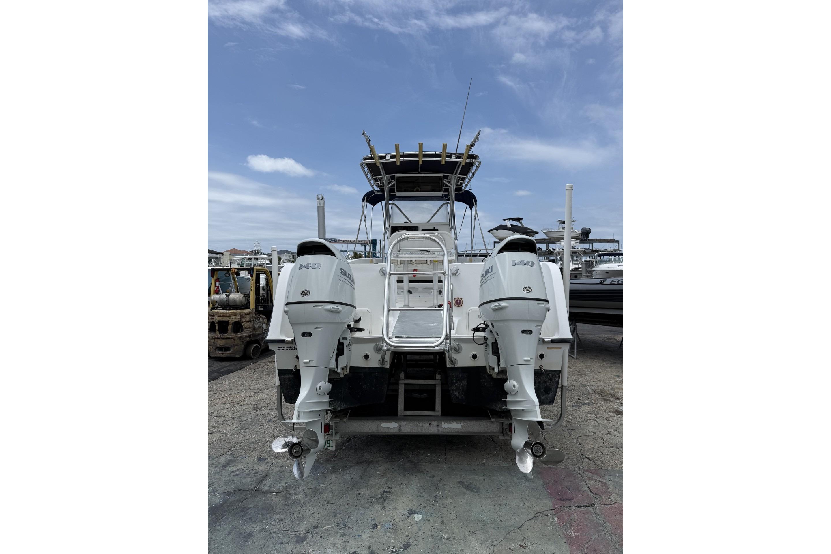2002 Pro Sports 2200 CC ProKat boat with dual Suzuki outboard motors, docked under a clear sky.