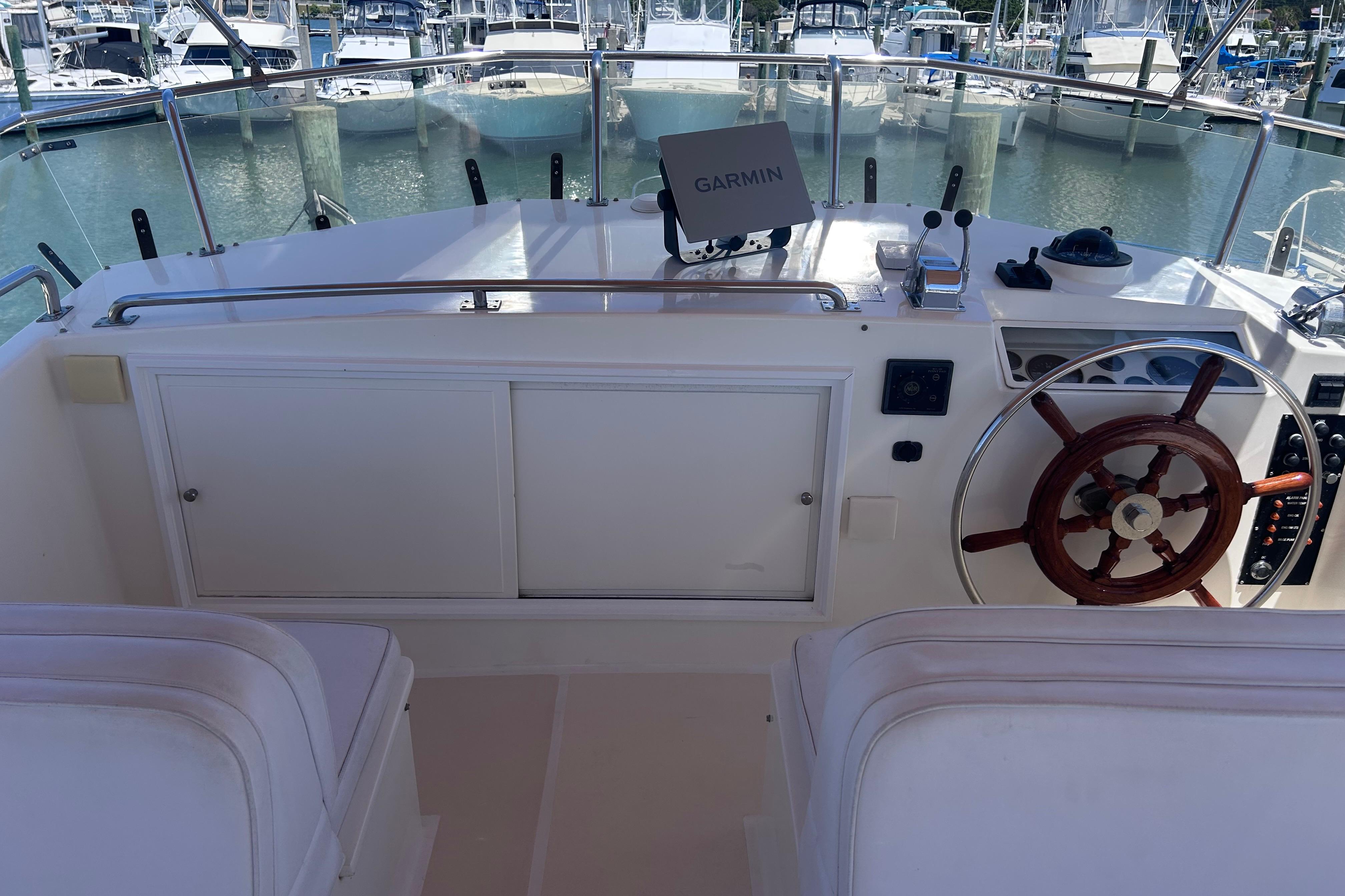 Helm of 1999 Grand Banks 42 Europa yacht with Garmin navigation, docked at marina.