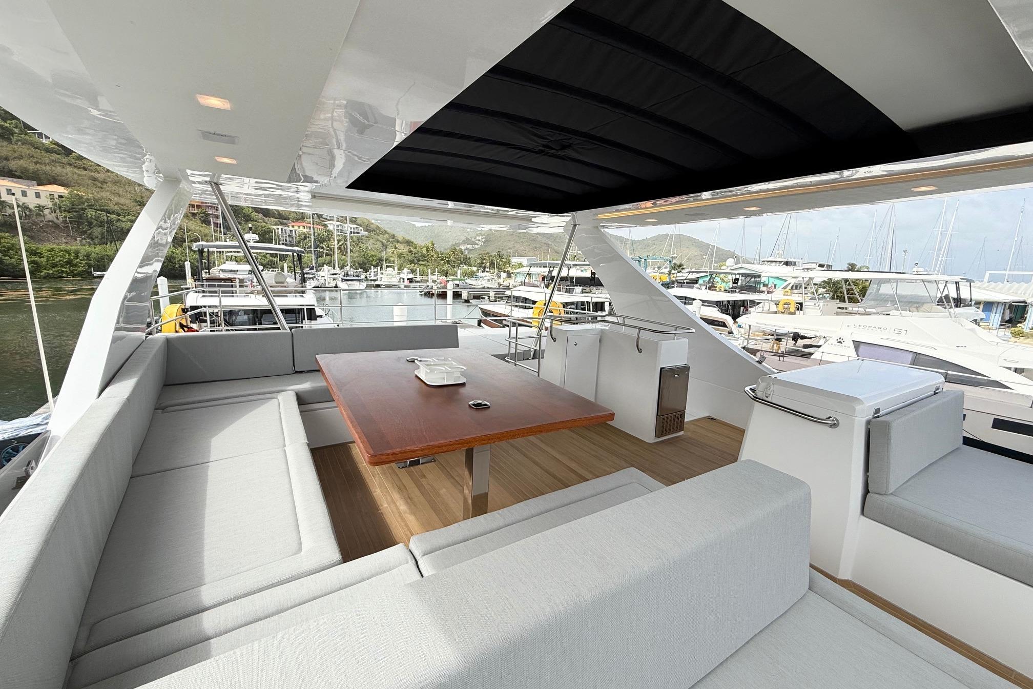 Luxurious 2026 Aventura 56 yacht deck with seating and table, docked at marina.