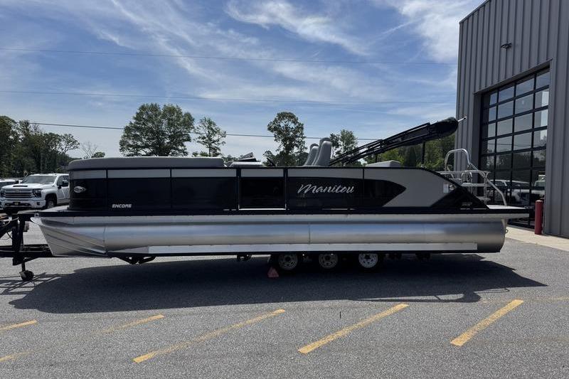 2026 Manitou Encore 25 SL SHP pontoon boat parked outdoors near a building.