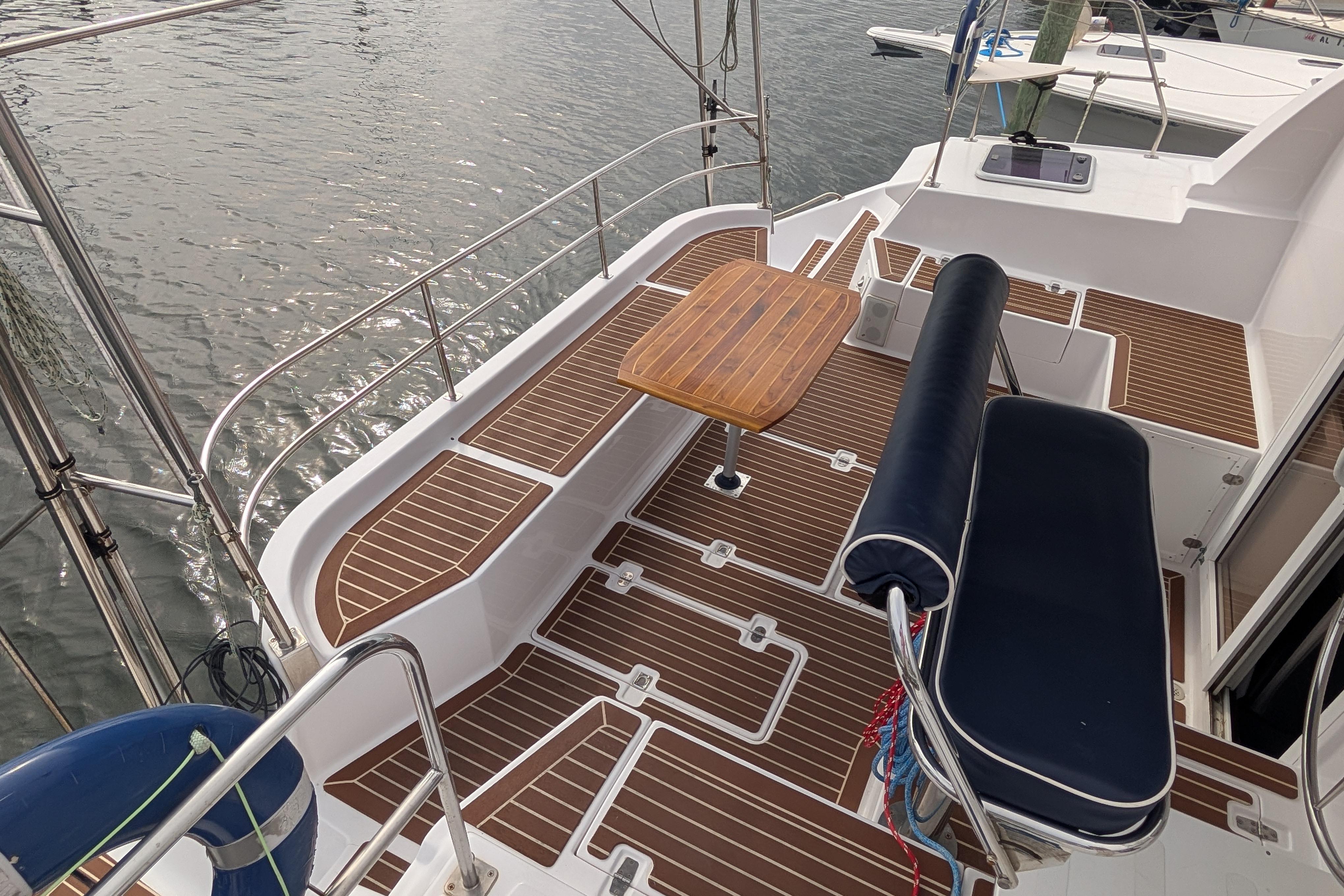 Spacious deck of 1999 Island Spirit 37 yacht with wooden table and cushioned seating.