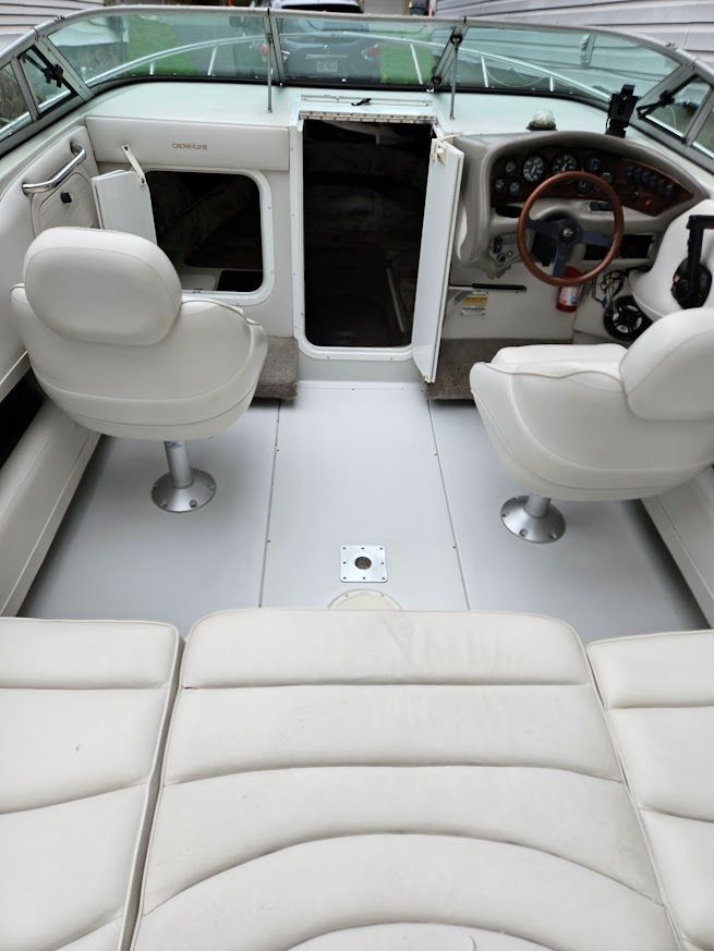 Interior view of a 1998 Crownline 210 CCR boat with white seats and a wooden steering wheel.