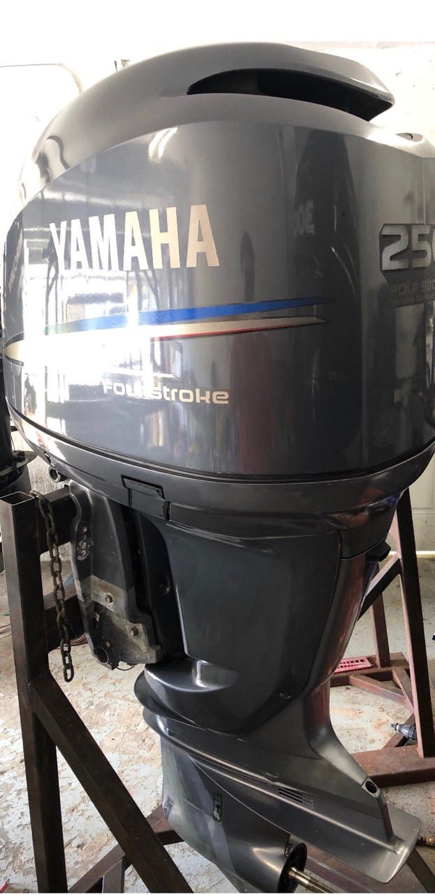A Yamaha 250 horsepower outboard motor mounted on a stand in a workshop setting.