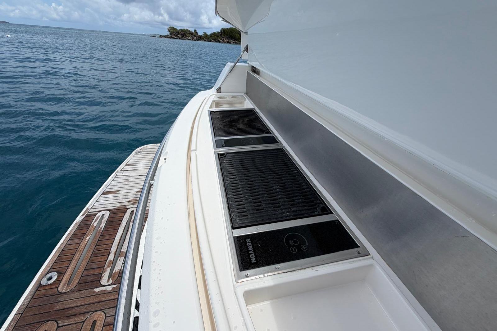 2018 Riviera 4800 Sport Yacht deck with grill, overlooking serene ocean waters.