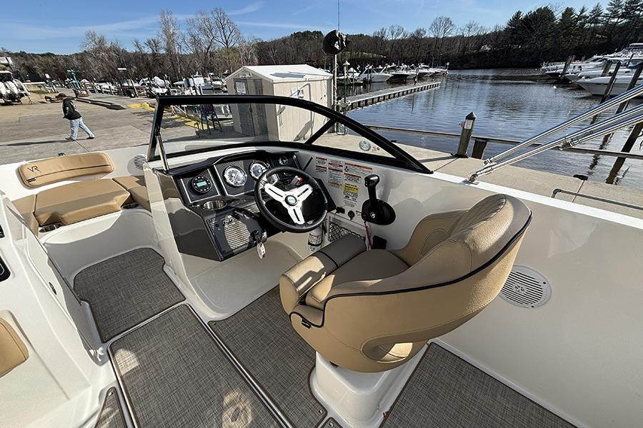 2023 Bayliner VR5 Bowrider OB interior with helm, steering wheel, and seating by the dock.