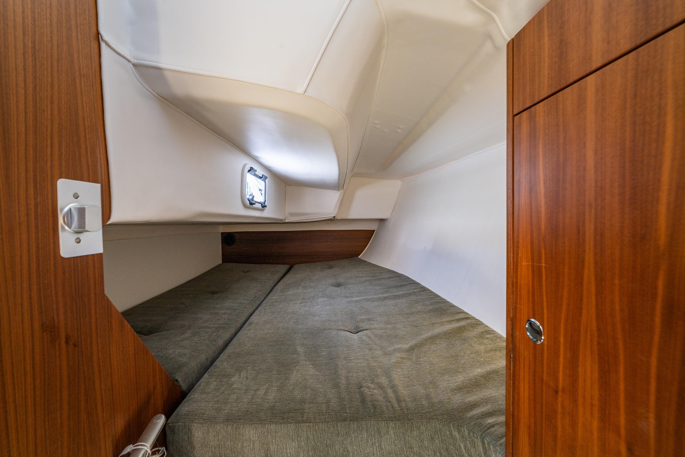 Interior cabin of 2018 J Boats J/97E, featuring cozy sleeping area and wooden cabinetry.