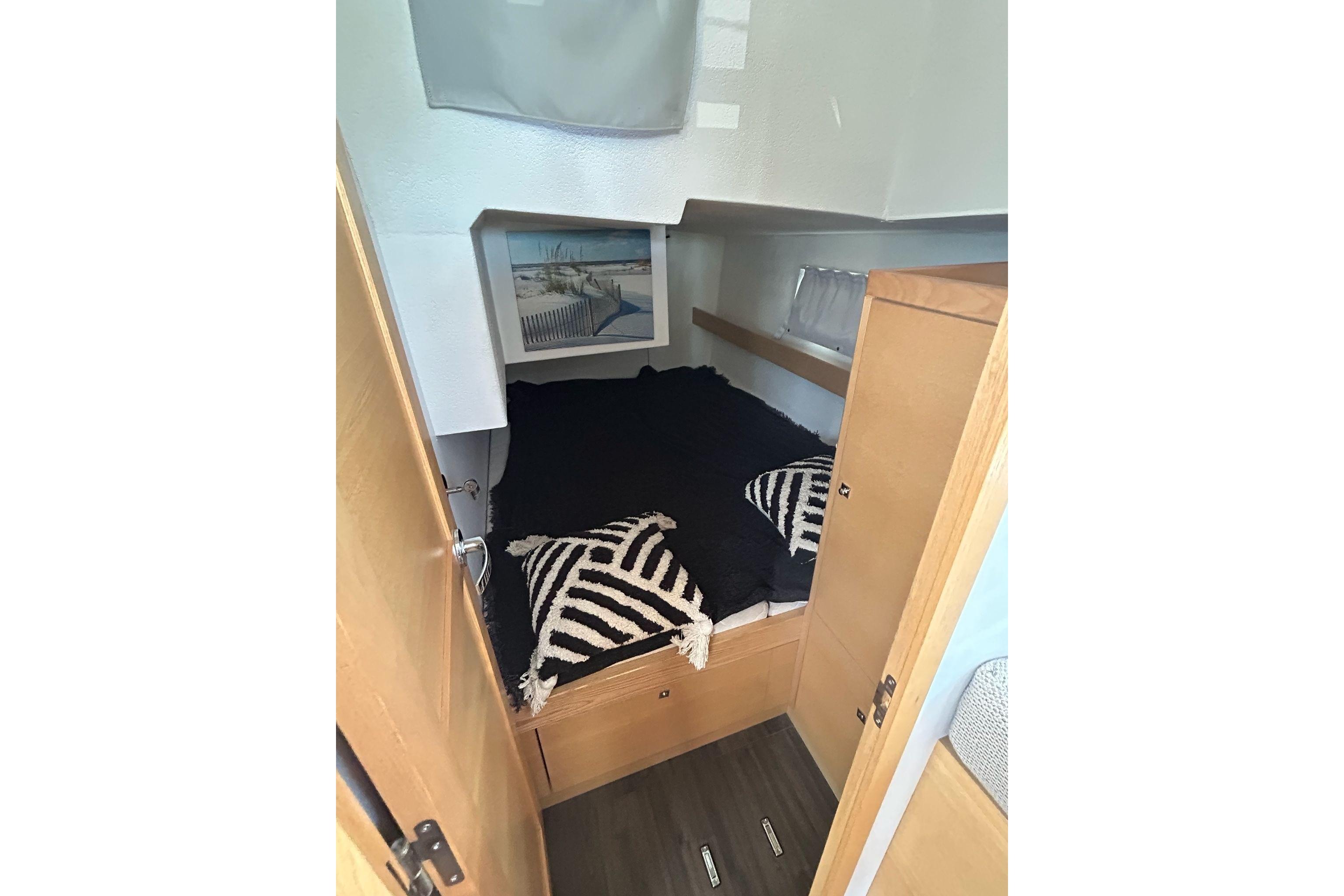 Cozy cabin interior of 2022 Alubat Ovni 370 sailboat with bed and decorative pillows.