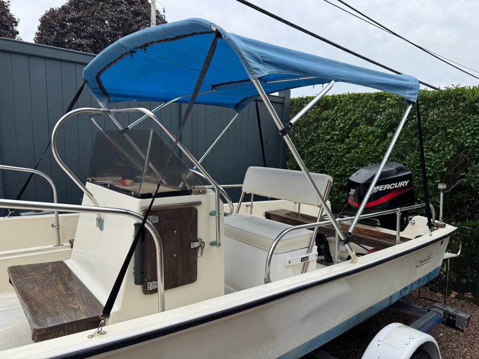A 1976 Boston Whaler 17 Montauk with a blue canopy and Mercury outboard motor.