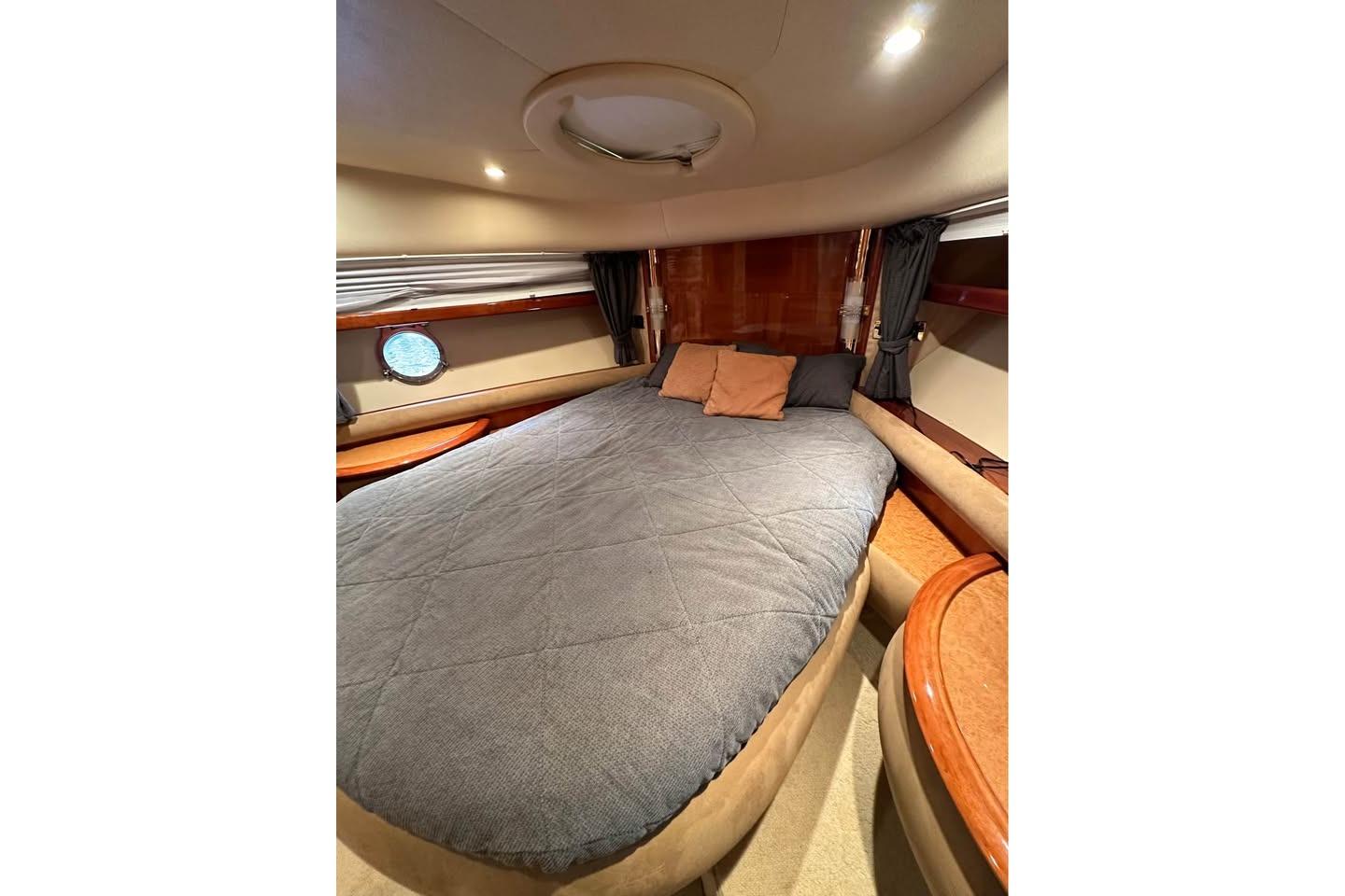 Luxurious bedroom interior of 2004 Azimut 55E yacht with cozy bedding and elegant wood accents.