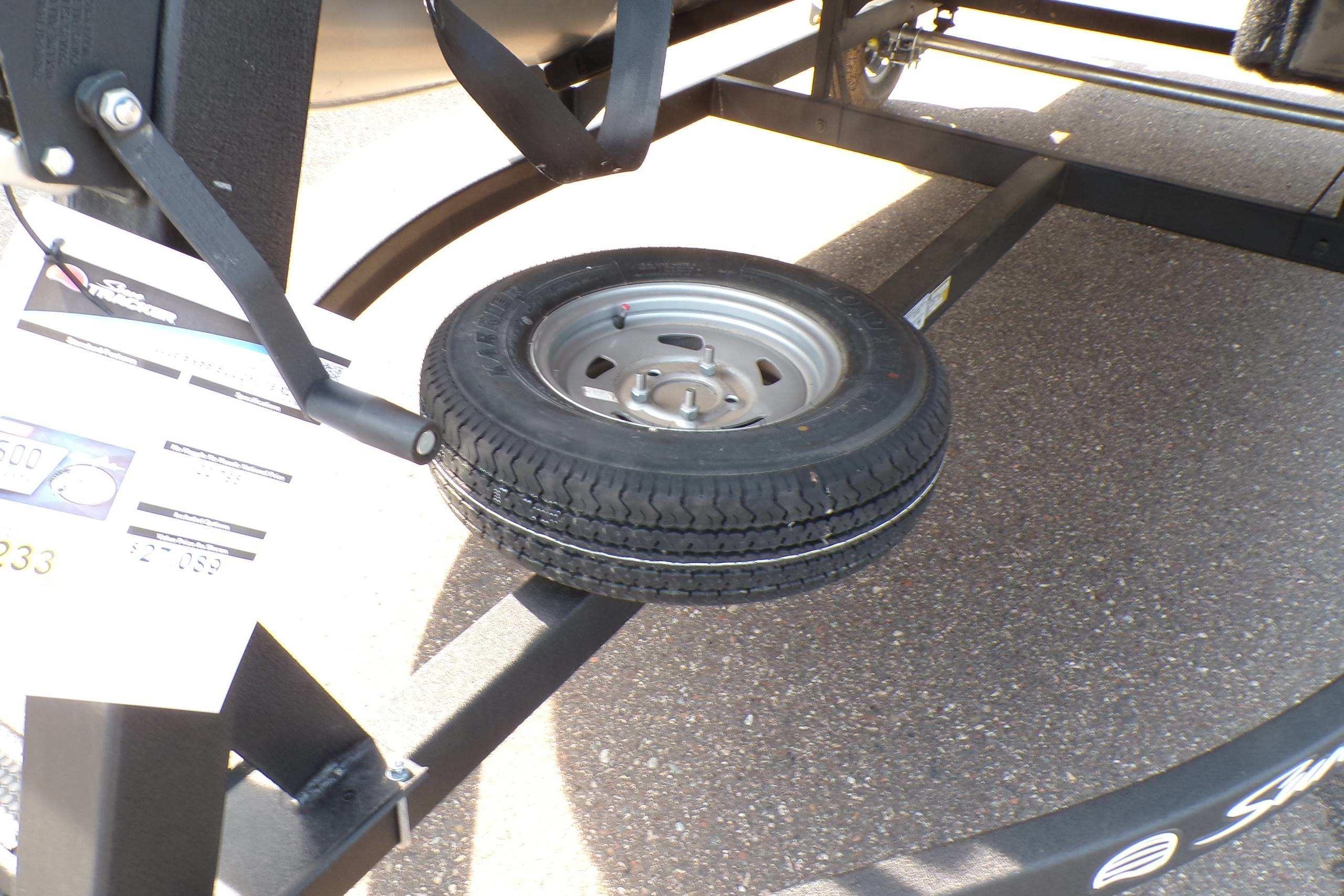 2026 Sun Tracker Bass Buggy 16 XL Select trailer with spare tire on asphalt.