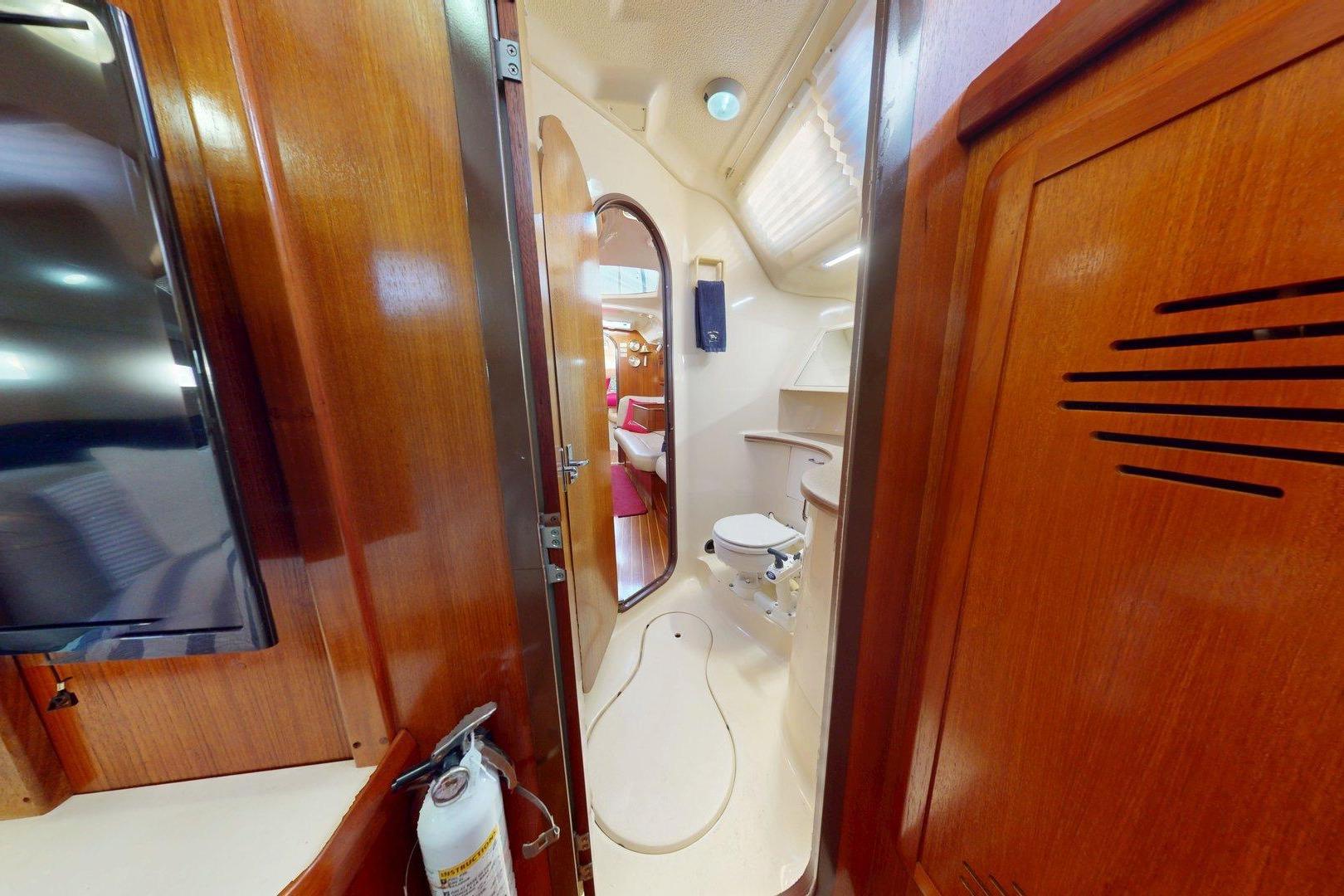 Interior of 1997 Hunter Legend 40.5 yacht, featuring wooden cabinetry and compact bathroom.