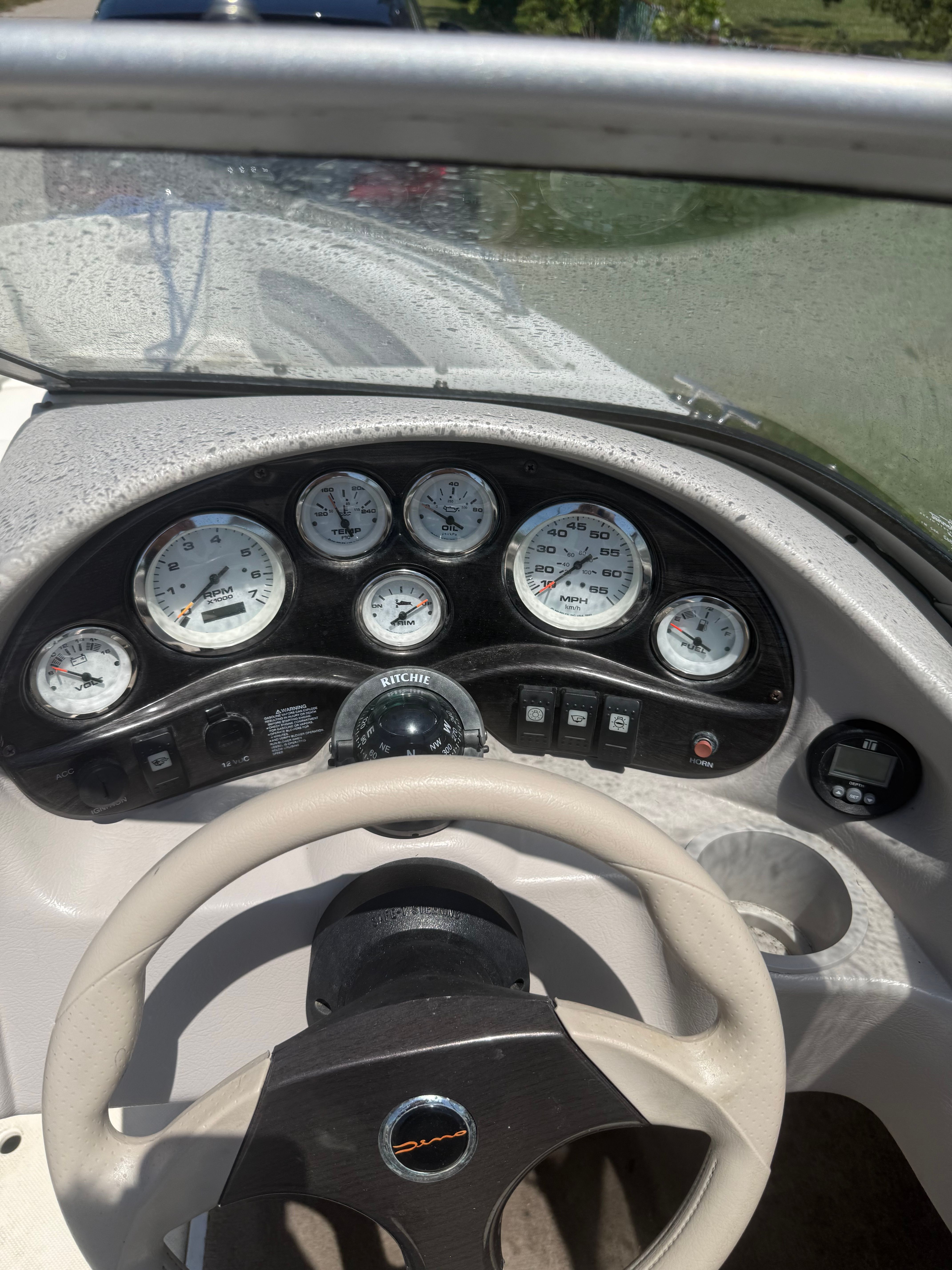 The image shows a boat dashboard with multiple gauges and a steering wheel.