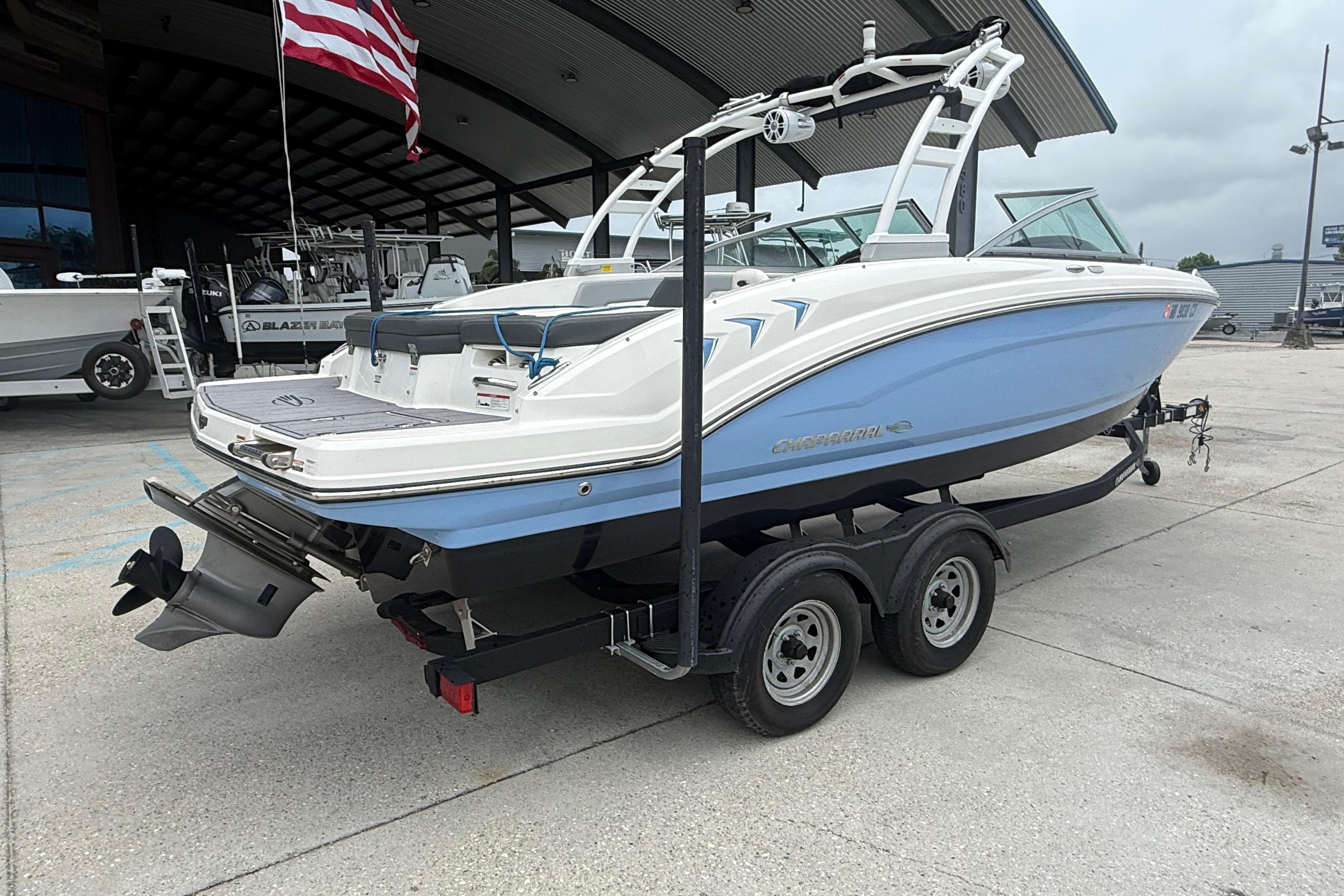 2023 Chaparral 230 SSi boat on trailer, displayed outdoors with American flag.