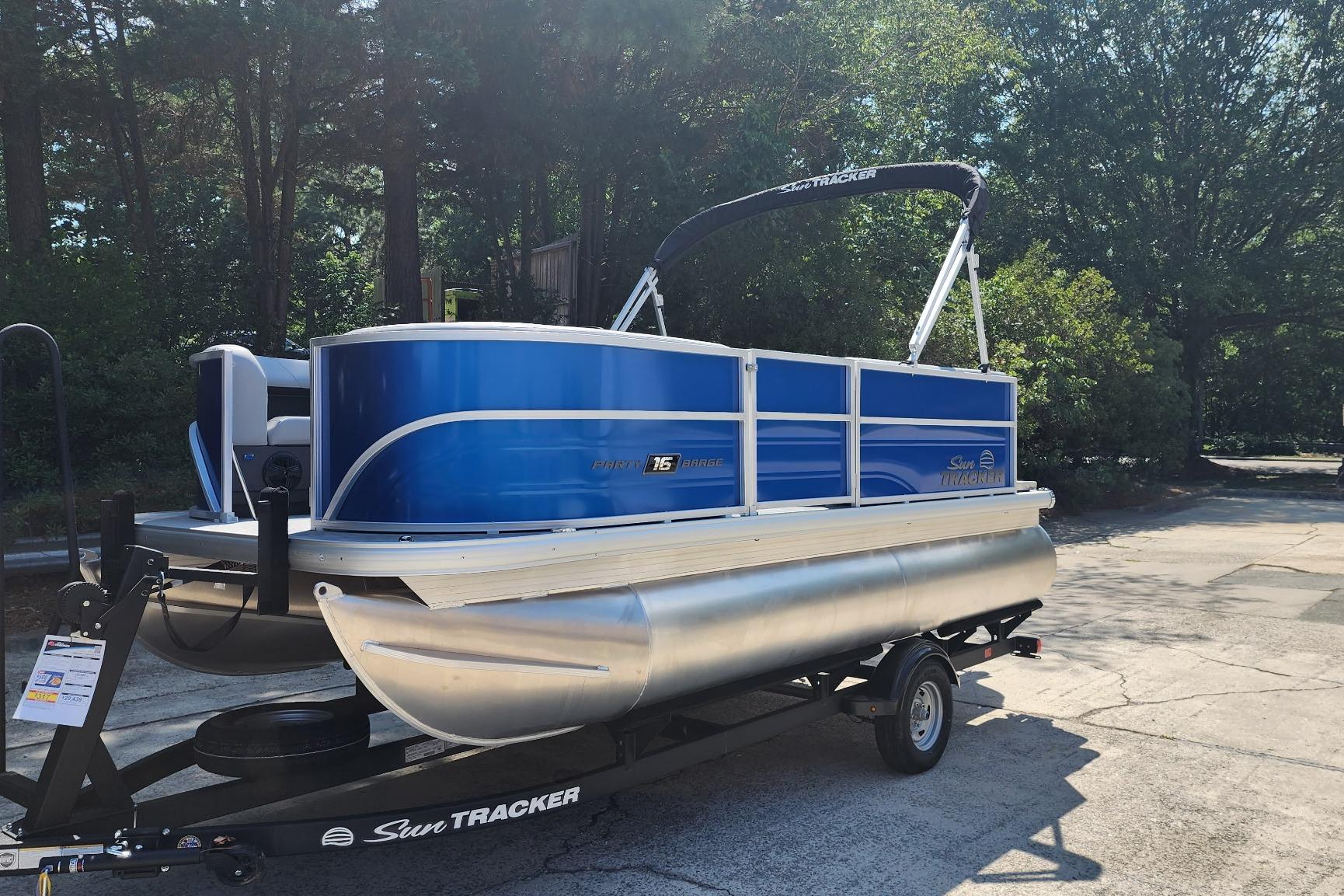 2026 Sun Tracker Party Barge 16 DLX pontoon boat on trailer, parked outdoors.